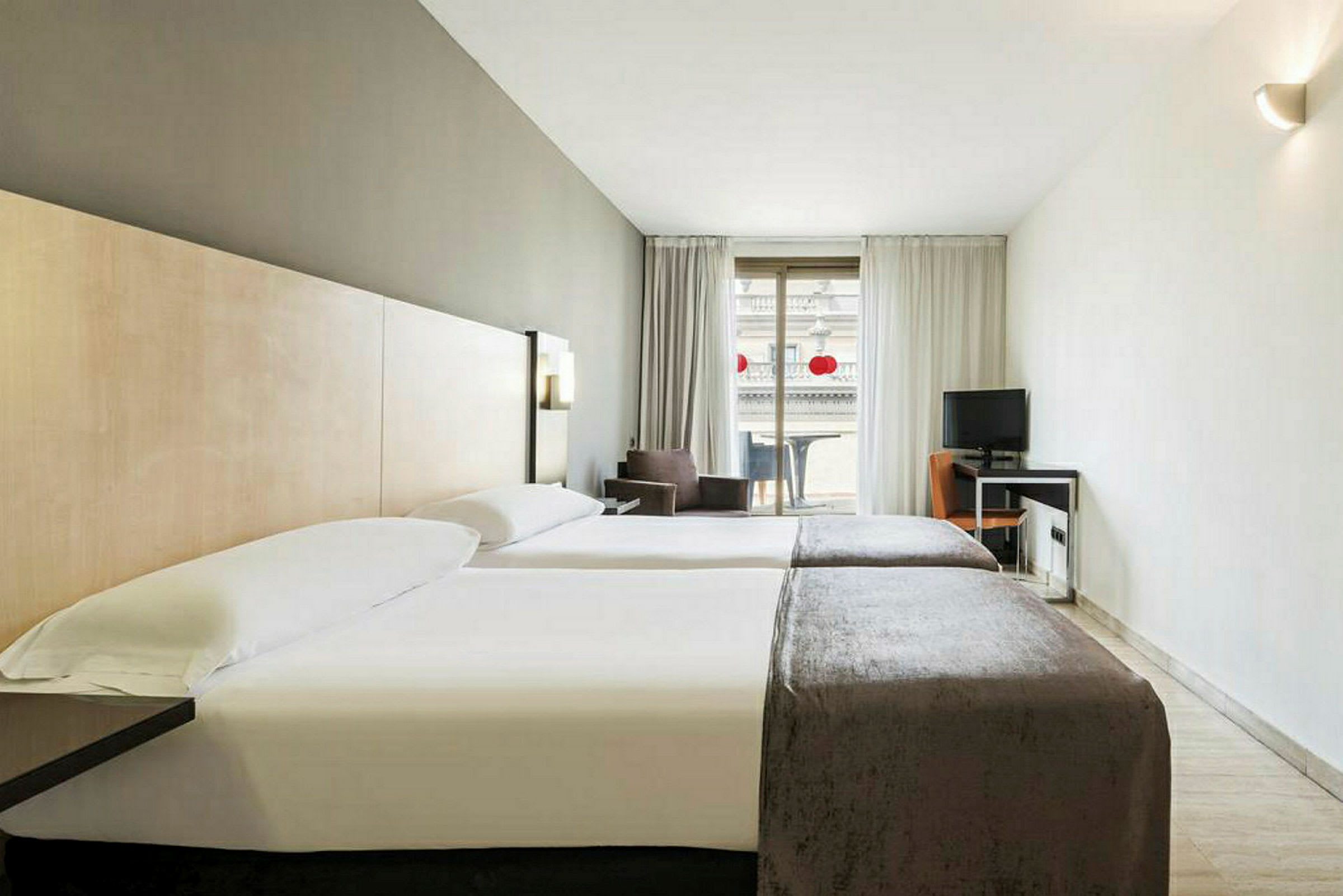 Hotellrum med två enkelsängar, skrivbord och balkong. (AI-genererad text)