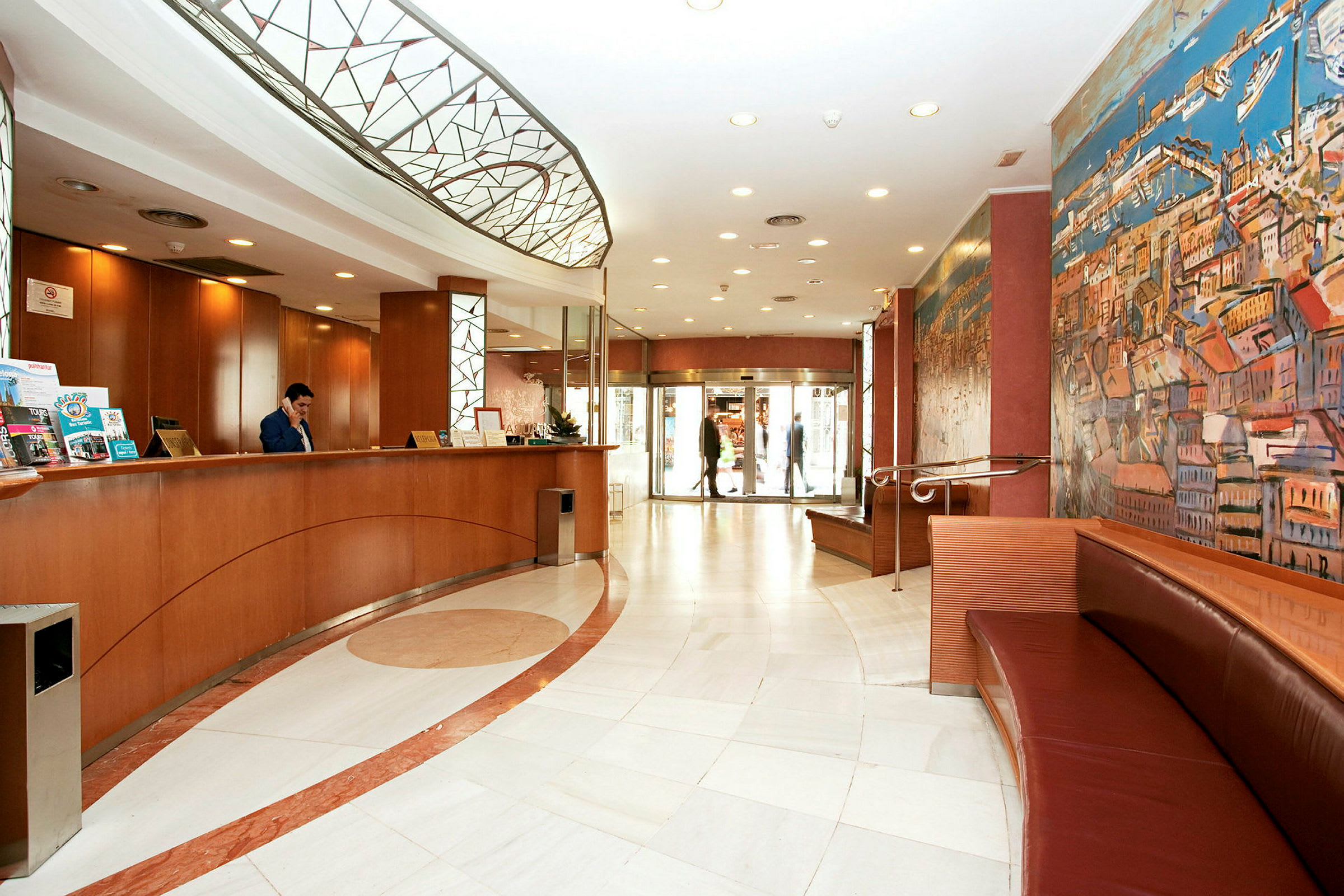 Bild av en hotellobby med reception, sittplatser och inredning i varma färger, inklusive en stor målning på väggen. (AI-genererad text)