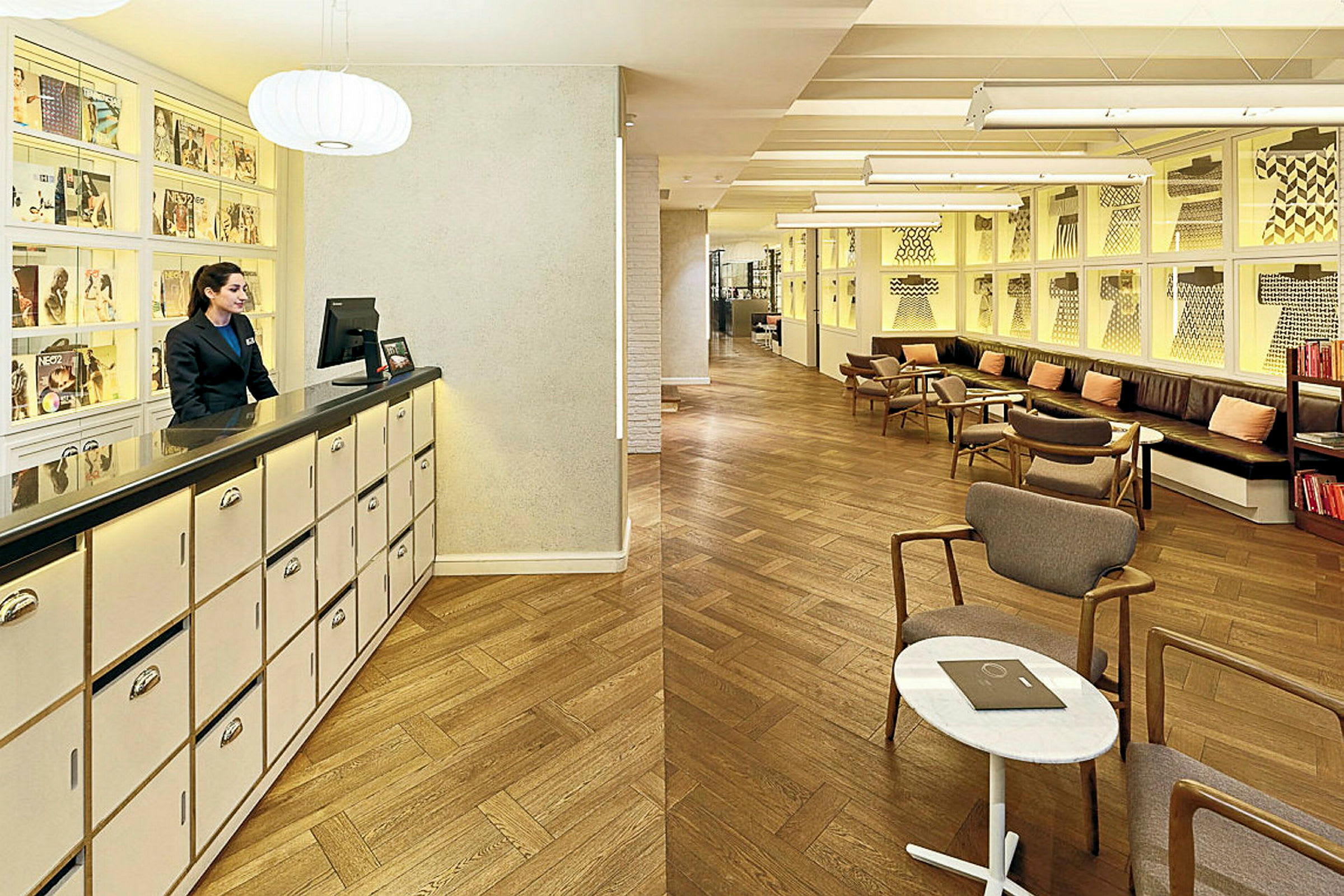 Receptionen i ett elegant hotell med modern inredning, trägolv och konst på väggarna. (AI-genererad text)