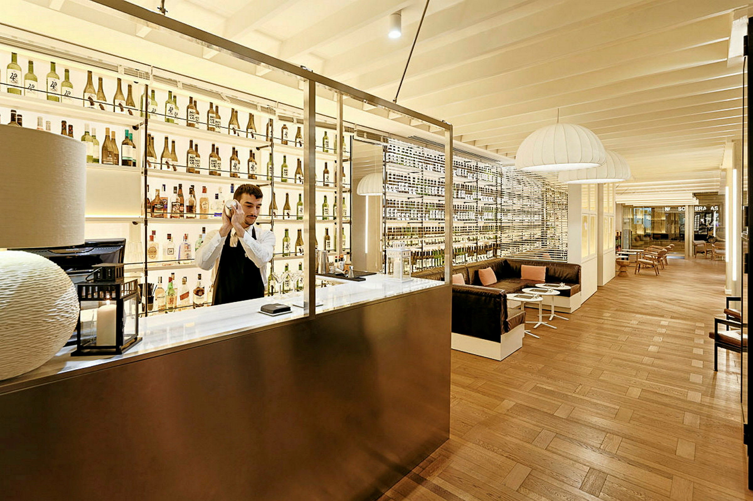 Ett elegant hotellbarområde med träinredning, hyllor fyllda med flaskor och en sittgrupp med soffor och bord. (AI-genererad text)