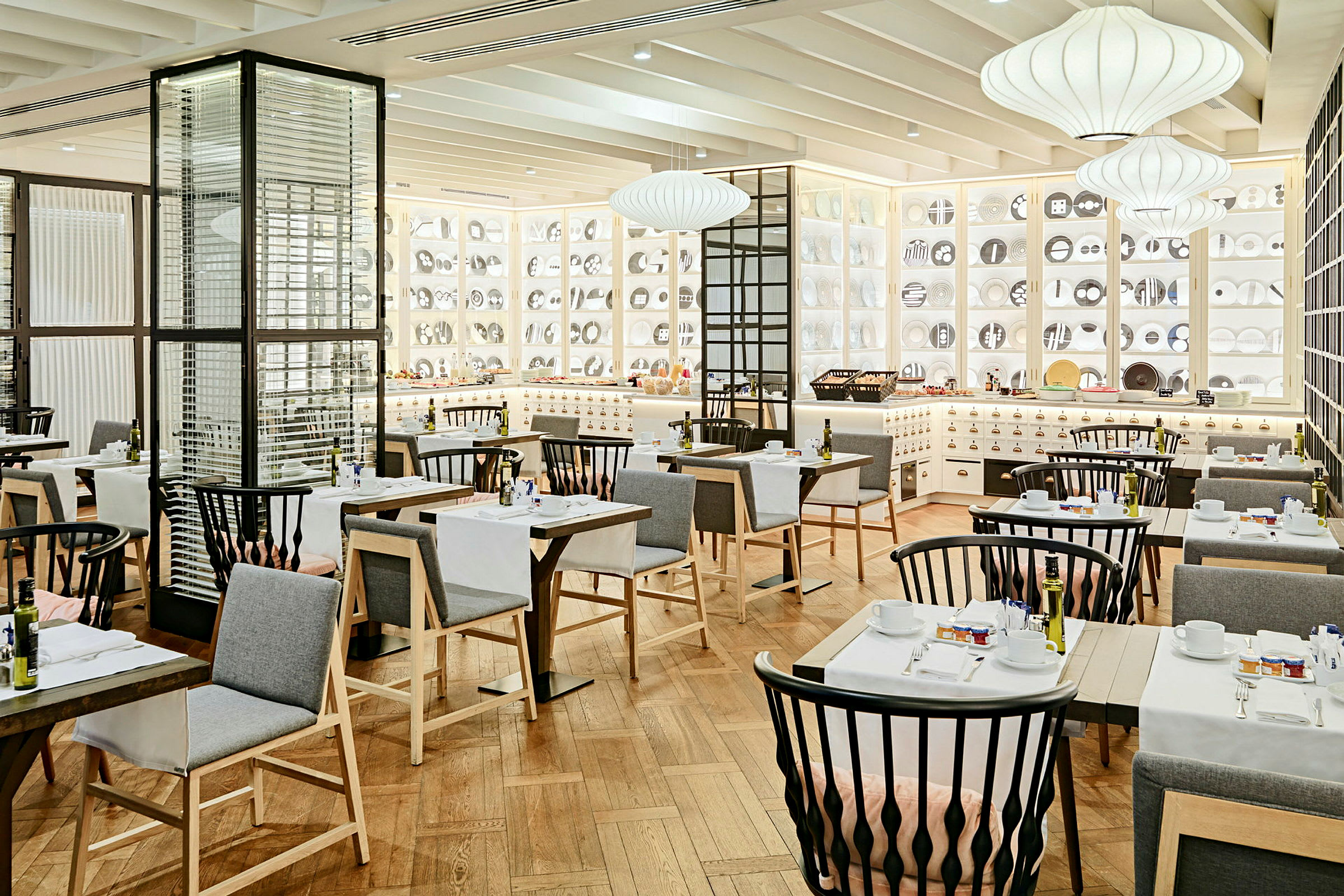 Ett elegant inrett restaurangutrymme med moderna möbler, vita väggar prydda med dekorativa föremål och mysig belysning. (AI-genererad text)