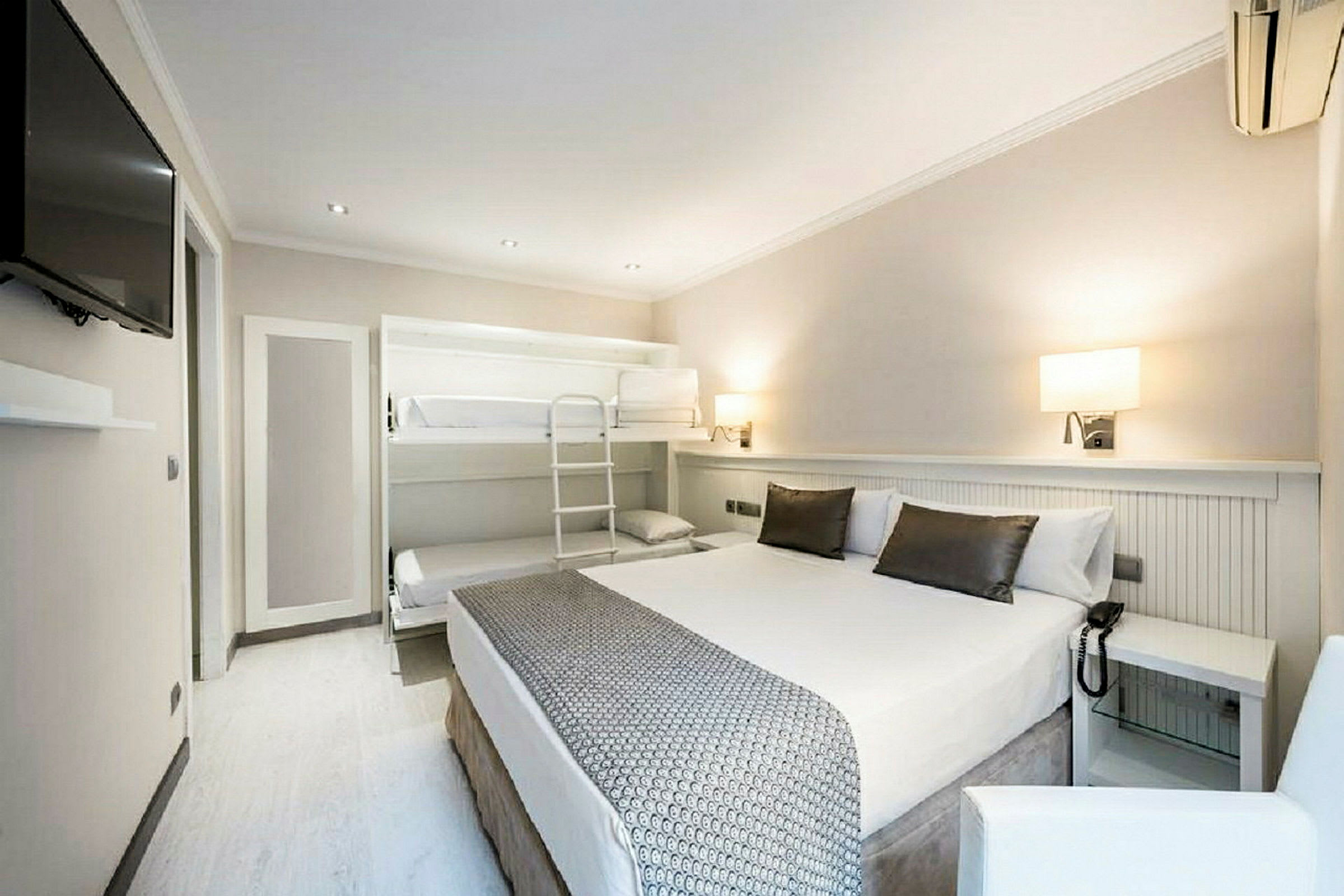 Ett hotellrum med en dubbelsäng, våningssäng och modern inredning. (AI-genererad text)