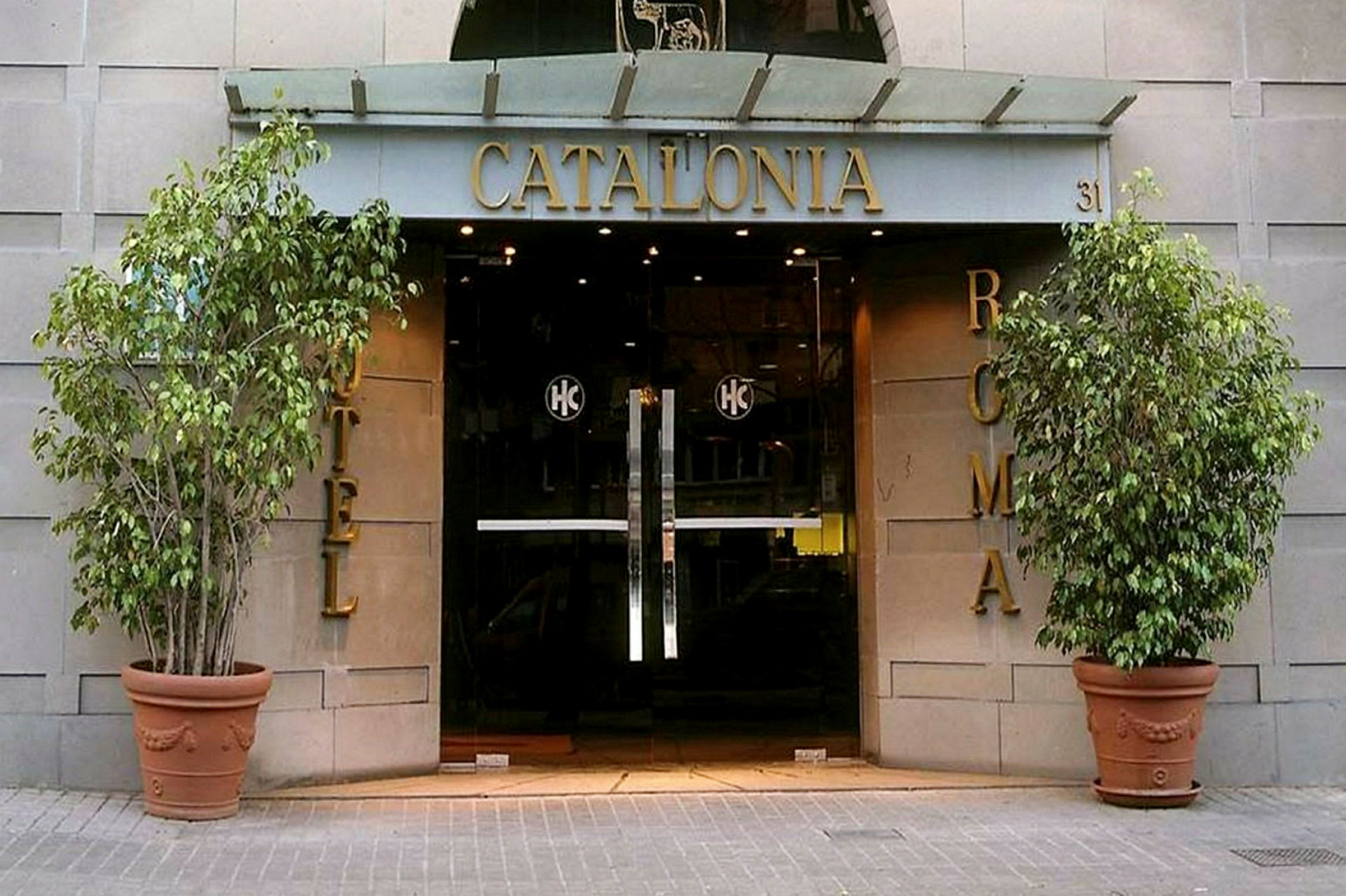Ingången till hotellet Catalonia Roma med glasdörrar och dekorationer. (AI-genererad text)