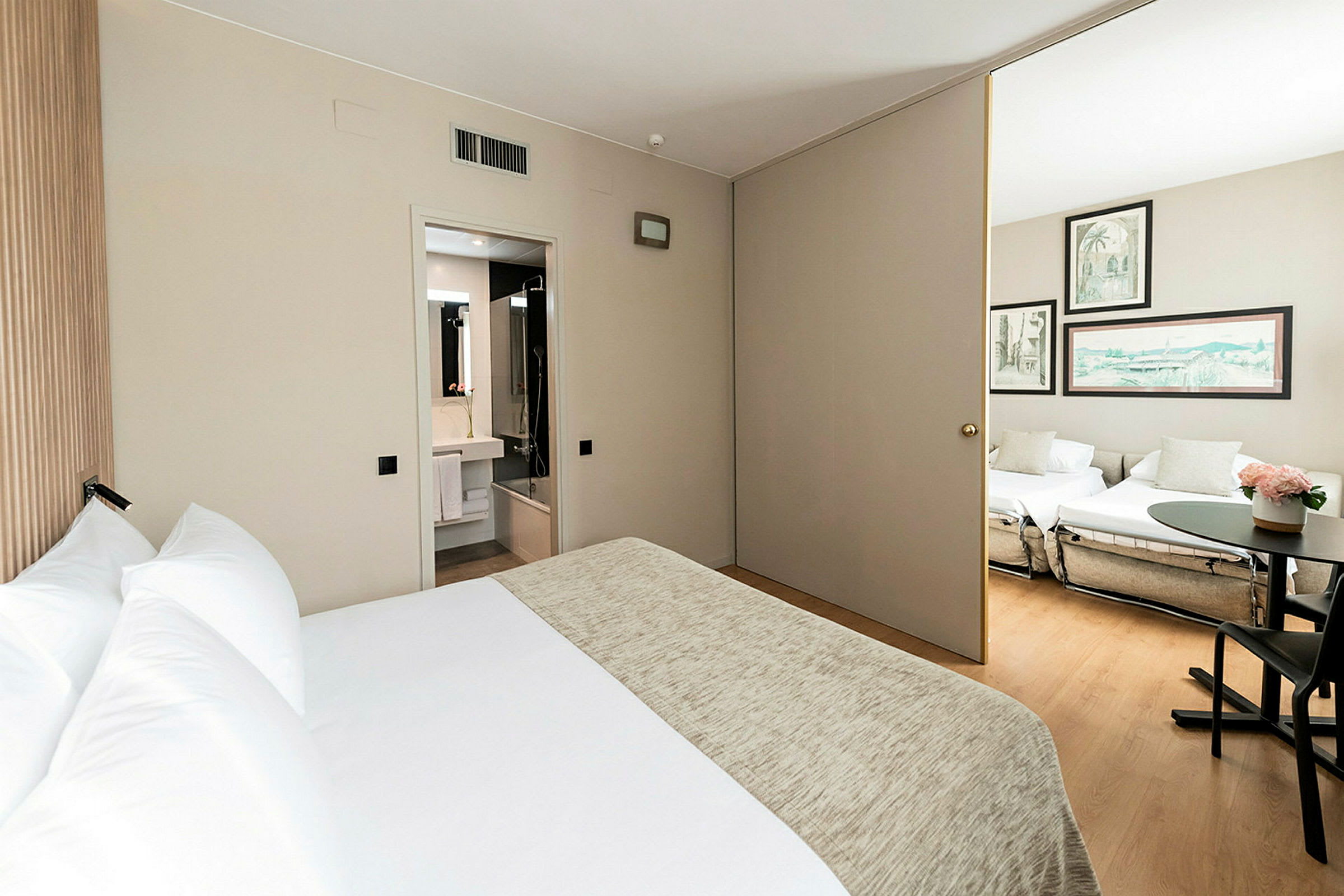 Ett hotellrum med en säng, ett badrum och en anslutande del med sittmöbler. (AI-genererad text)