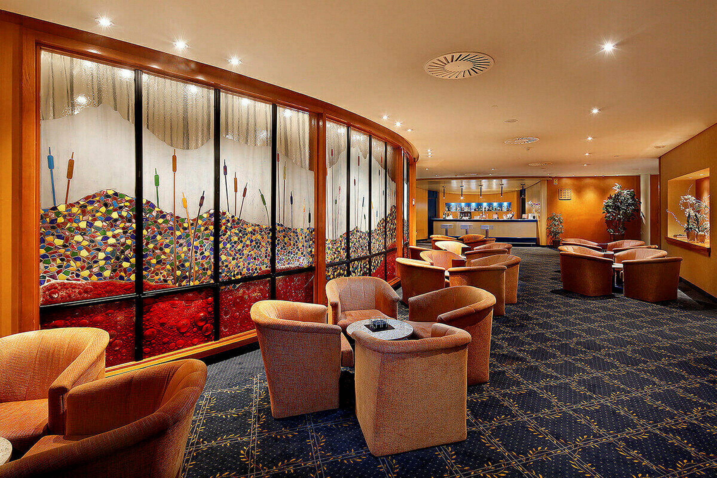 En elegant lounge med fåtöljer och bord, dekorerad med en färgglad väggmålning och heltäckningsmatta. (AI-genererad text)
