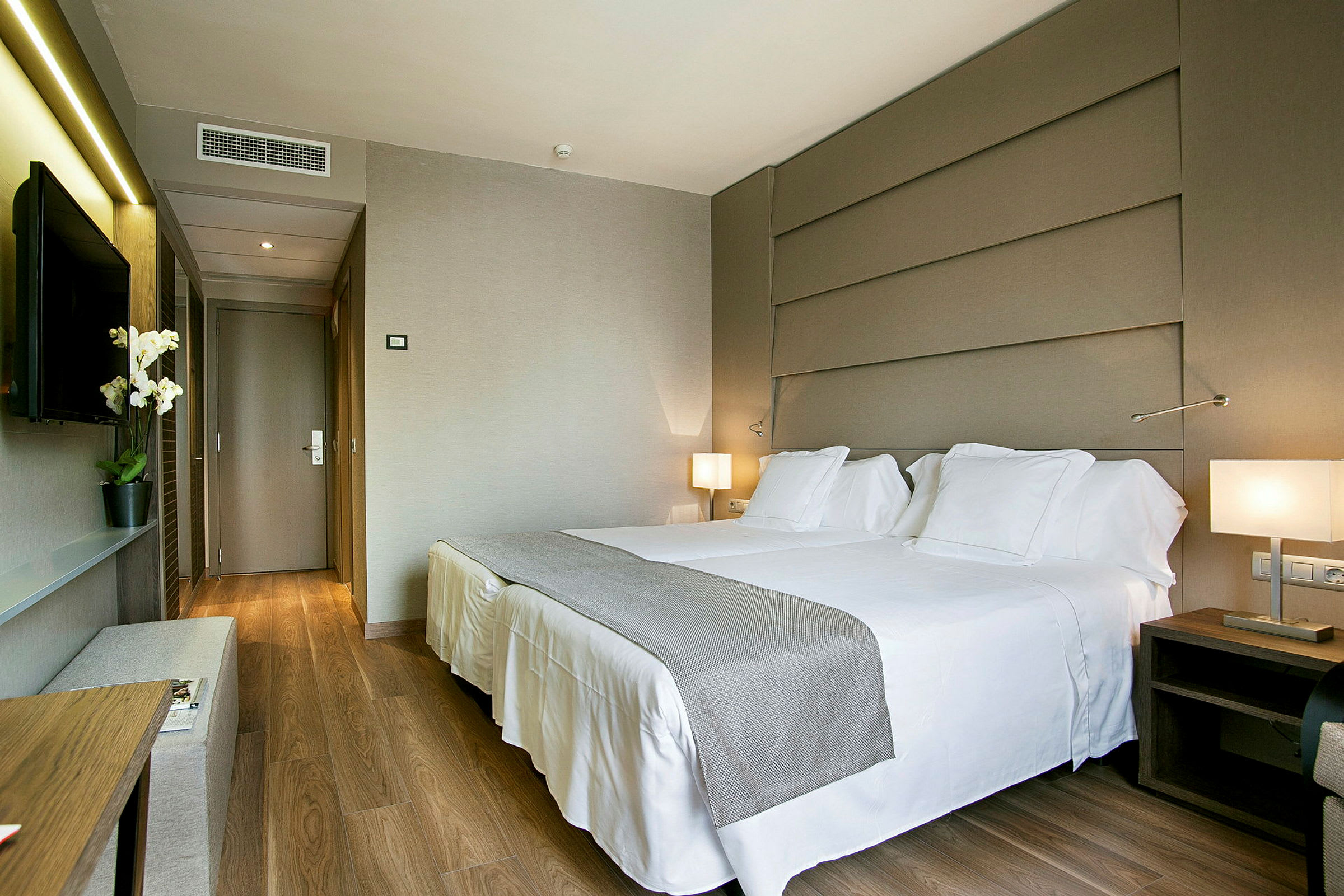 Ett hotellrum med en dubbelsäng, väggmonterad TV och modern inredning. (AI-genererad text)