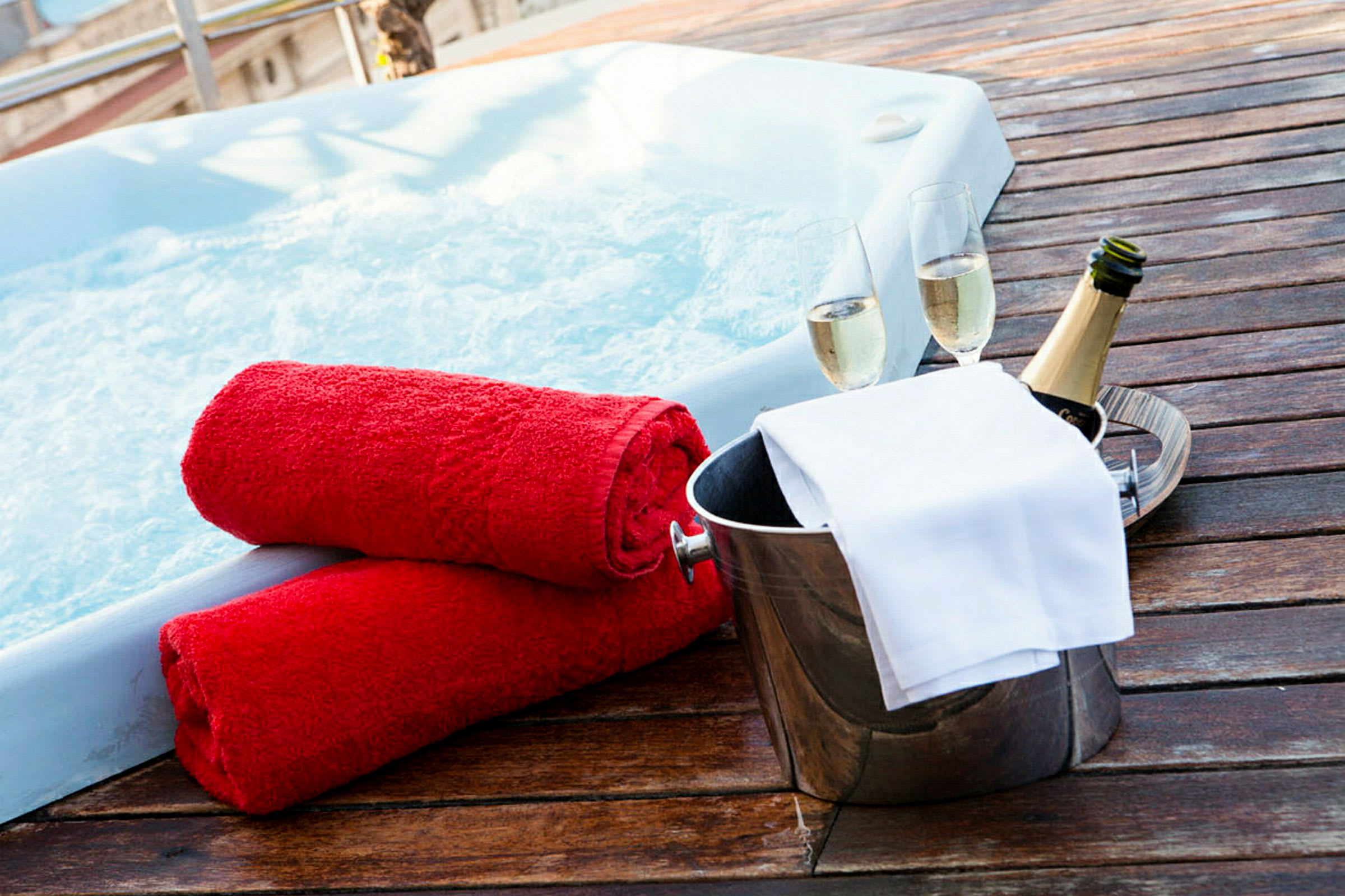 Här syns en bubbelpool med två röda handdukar och en bricka med champagneflaska och glas. (AI-genererad text)