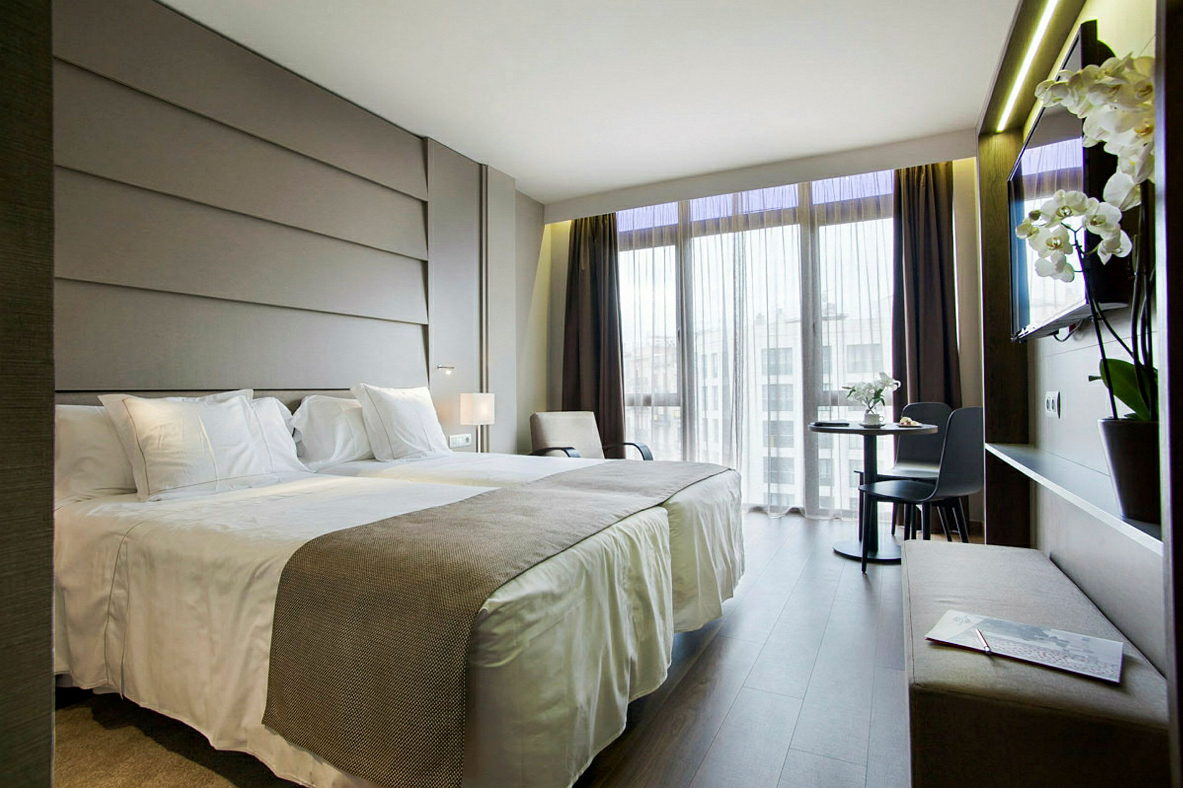 Bild av ett modernt hotellrum med två enkelsängar, ett skrivbord och en TV. (AI-genererad text)