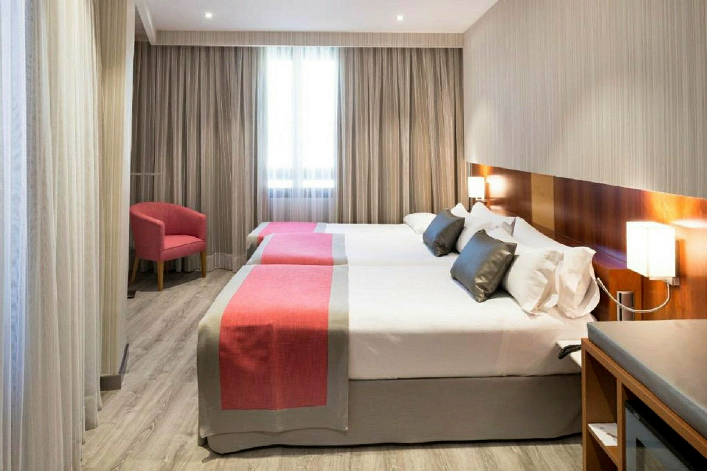 Hotellrum med två separata sängar, enkla moderna möbler och ett fönster i bakgrunden. (AI-genererad text)
