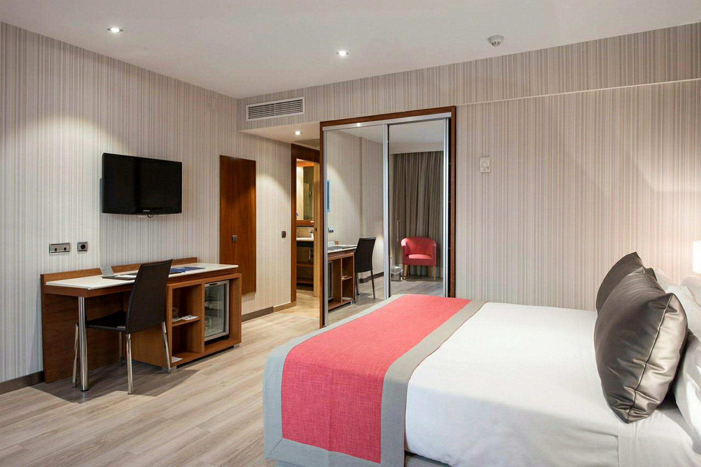 Ett modernt hotellrum med en säng och ett skrivbord med stol. (AI-genererad text)