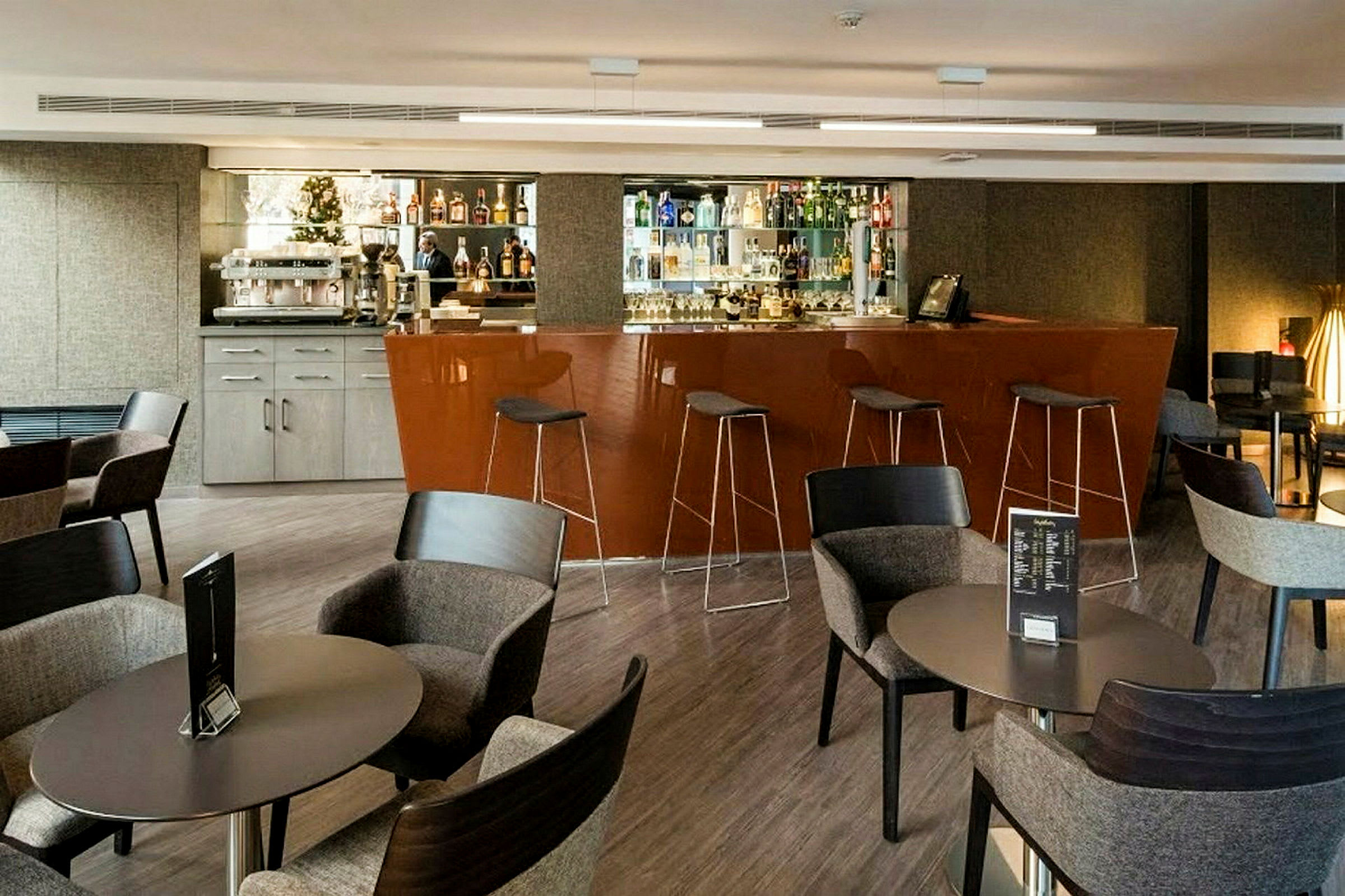 Moderna caféstolar och bord framför en välfylld hotelbar. (AI-genererad text)