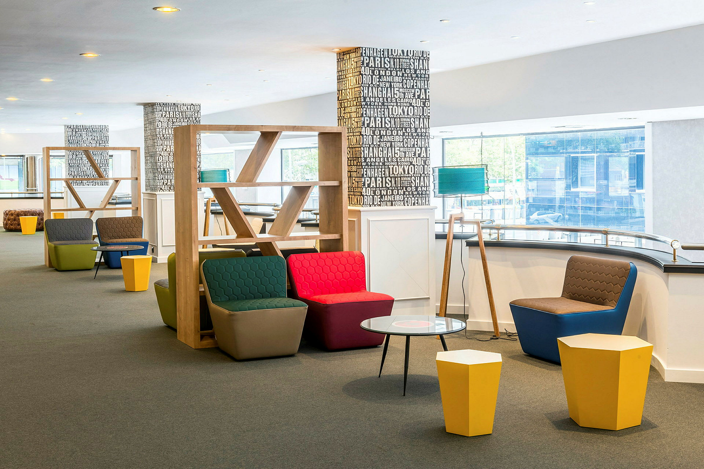 En modern lounge med färgglada sittmöbler, små bord och hyllor i trä. (AI-genererad text)