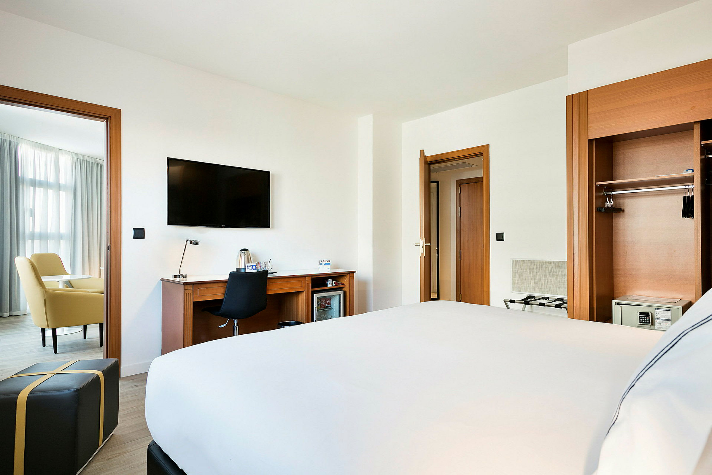 Hotellrum med en säng, skrivbord, TV och sittgrupp. (AI-genererad text)