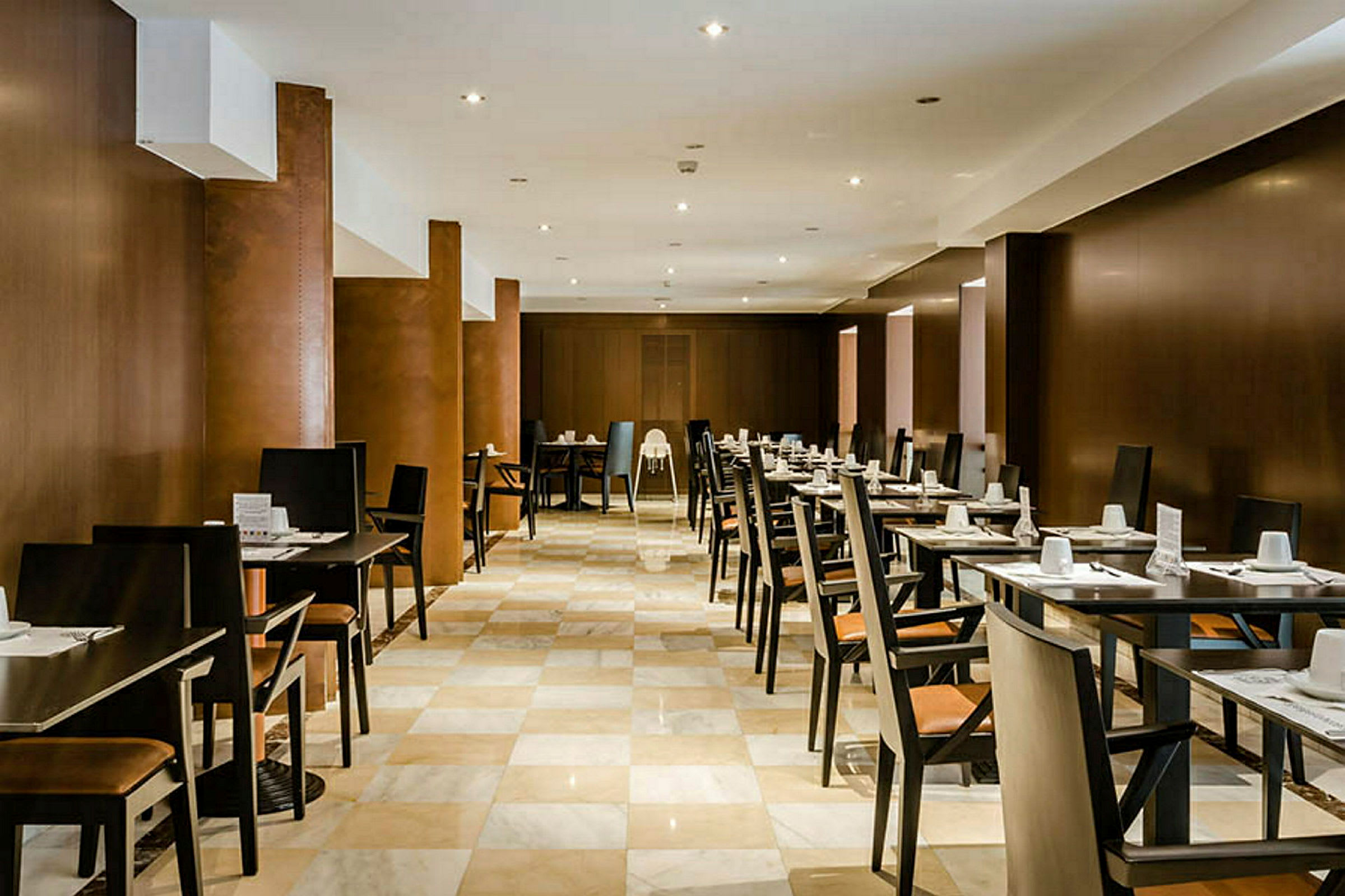 Ett restaurangutrymme med rader av bord och stolar, dukade för gäster. (AI-genererad text)
