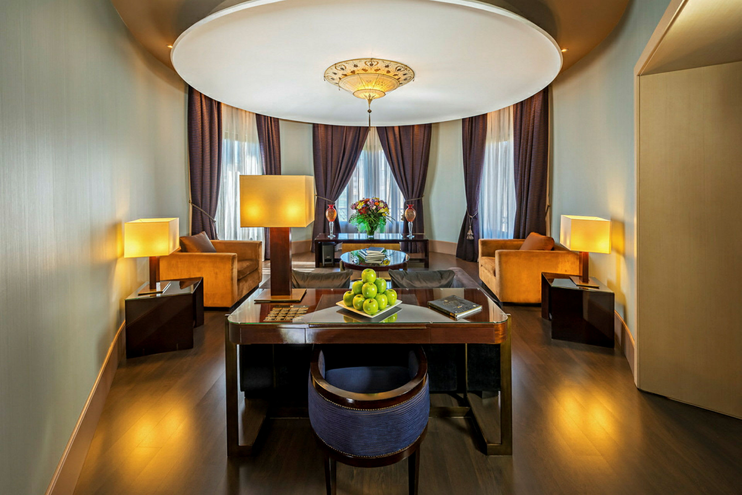 Ett elegant hotellrum med sittgrupp, skrivbord, soffor, lampor och atmosfärisk belysning. (AI-genererad text)