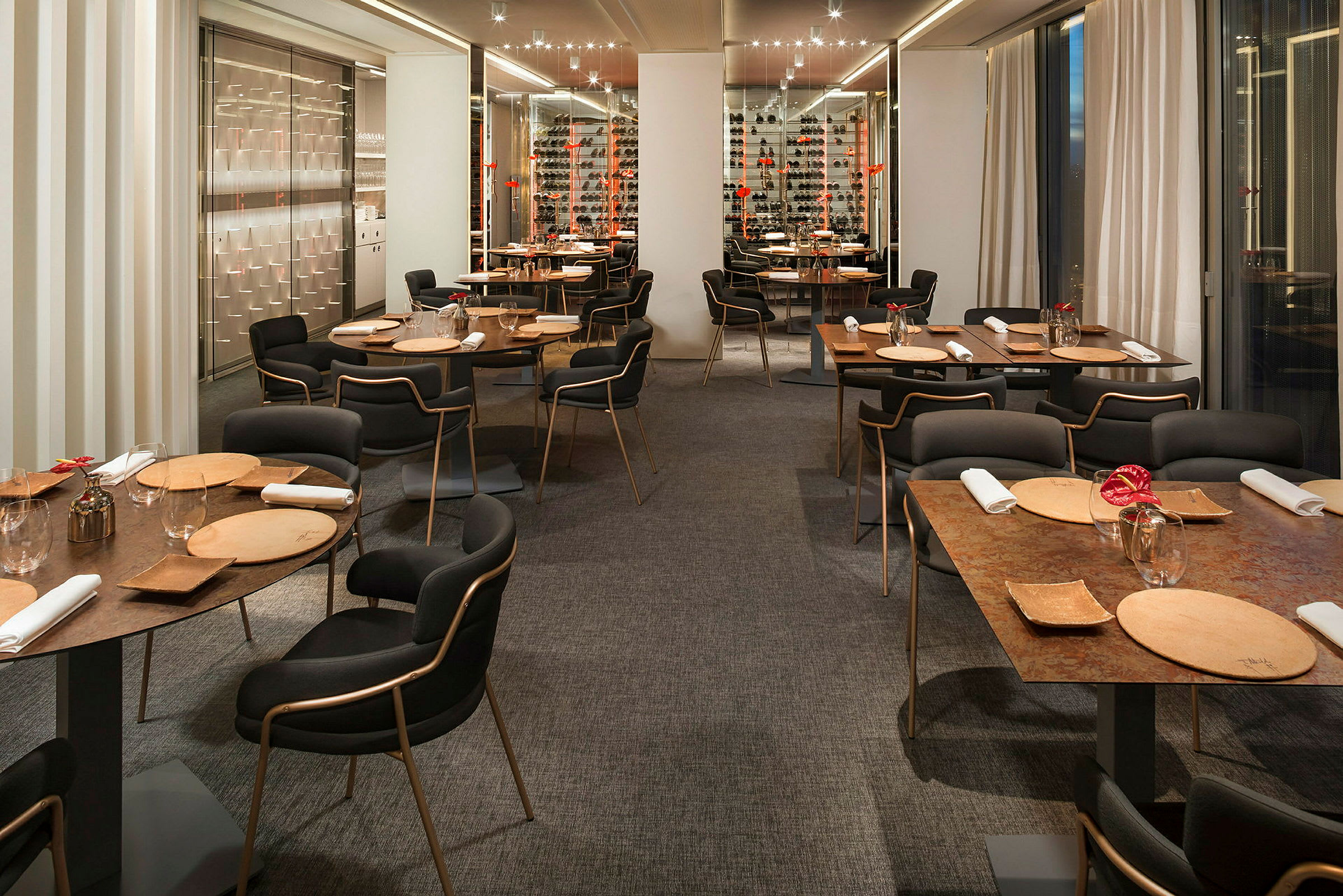 En restaurang med modern inredning, bord dukade med tallrikar, glas och servetter. (AI-genererad text)