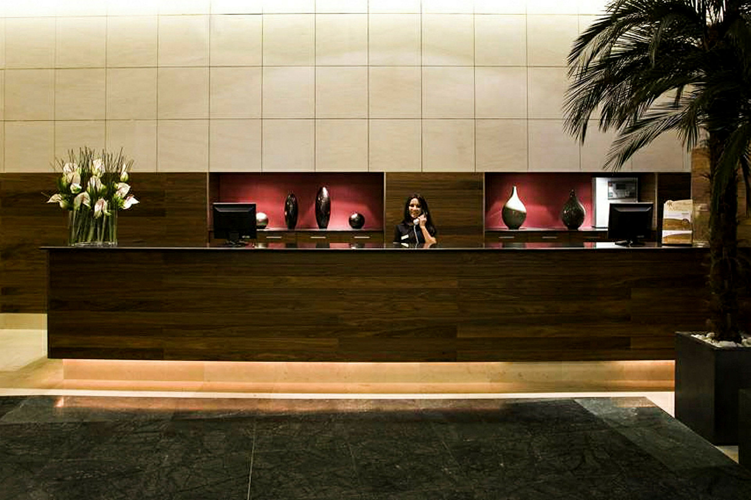 En receptionsdisk med träpaneler, dekorerad med moderna vaser och en blomsterbukett på ena sidan. (AI-genererad text)