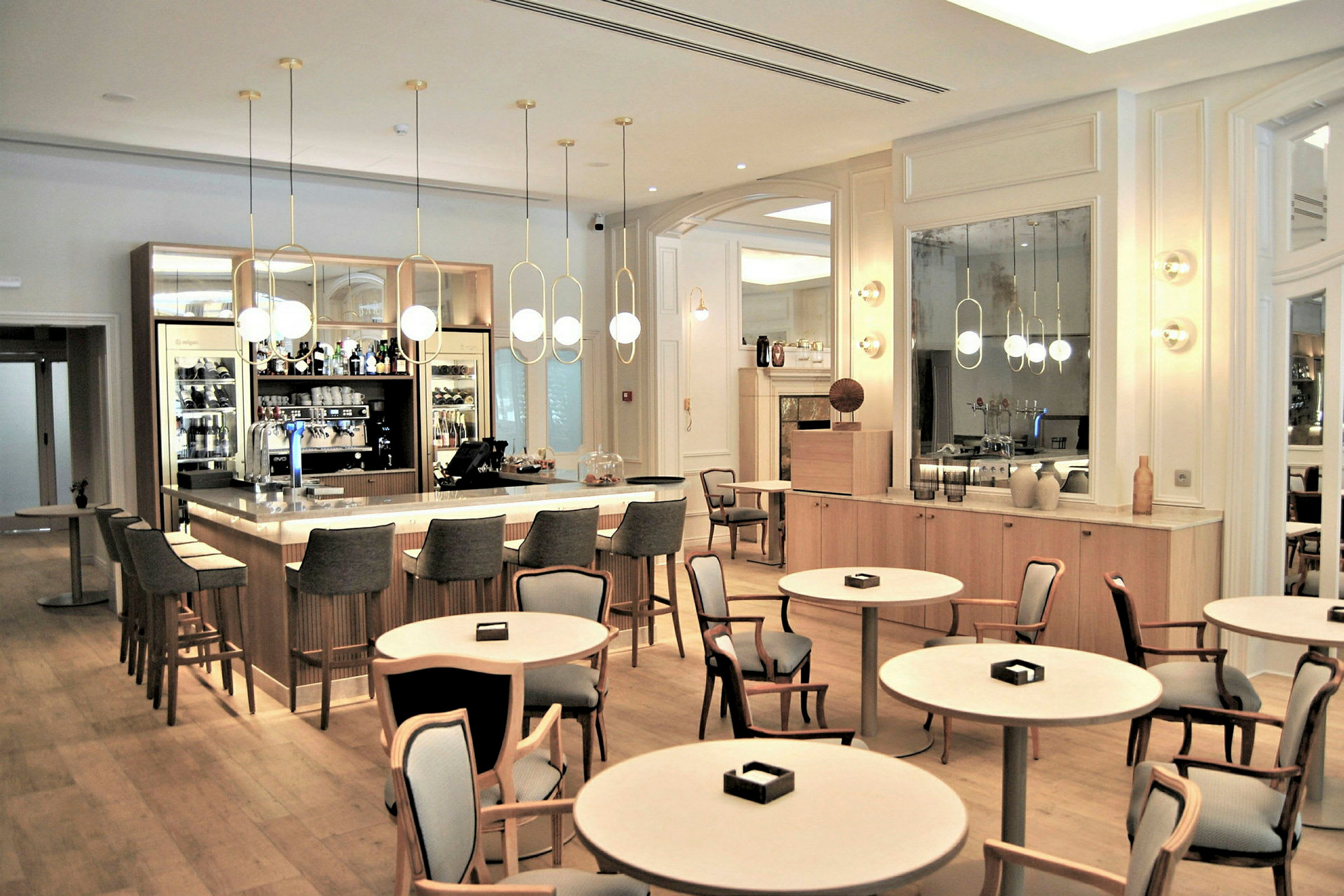 En elegant bar med ett stort rundat bord och stolar i en ljus, modern inredning. (AI-genererad text)