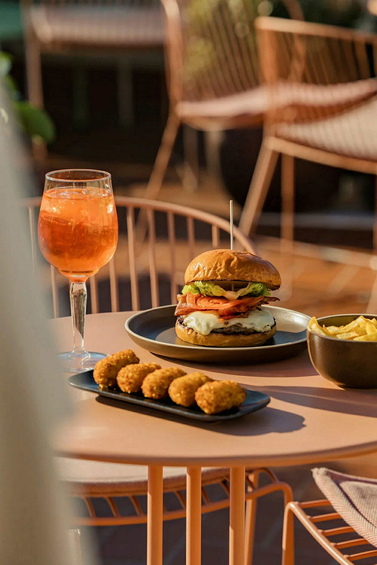 En tallrik med hamburgare och pommes frites, bredvid en bricka med små tilltugg och ett glas orange dryck. (AI-genererad text)