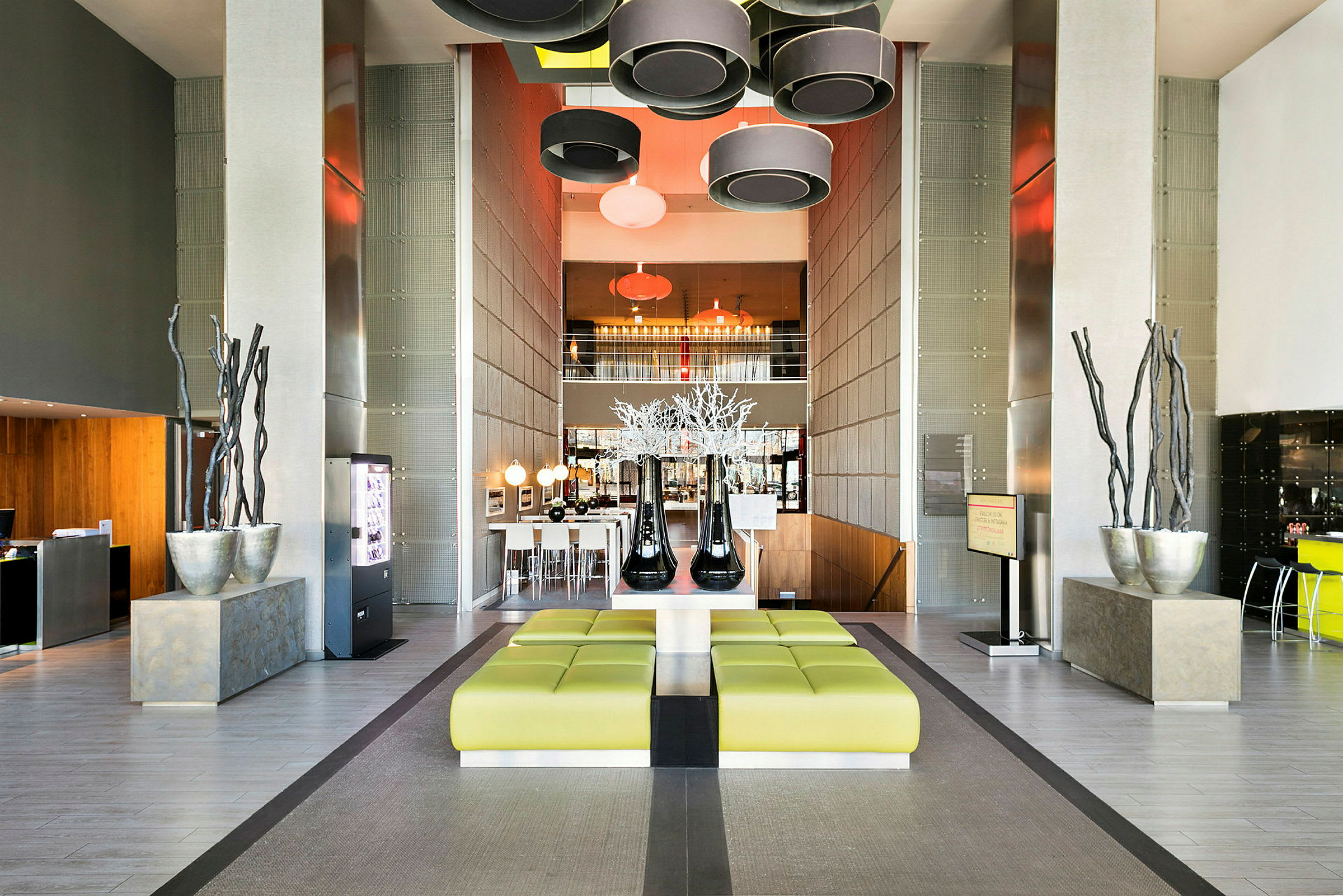 Modernt inrett hotellobby med gröna sittplatser, dekorativa element och hängande lampor. (AI-genererad text)