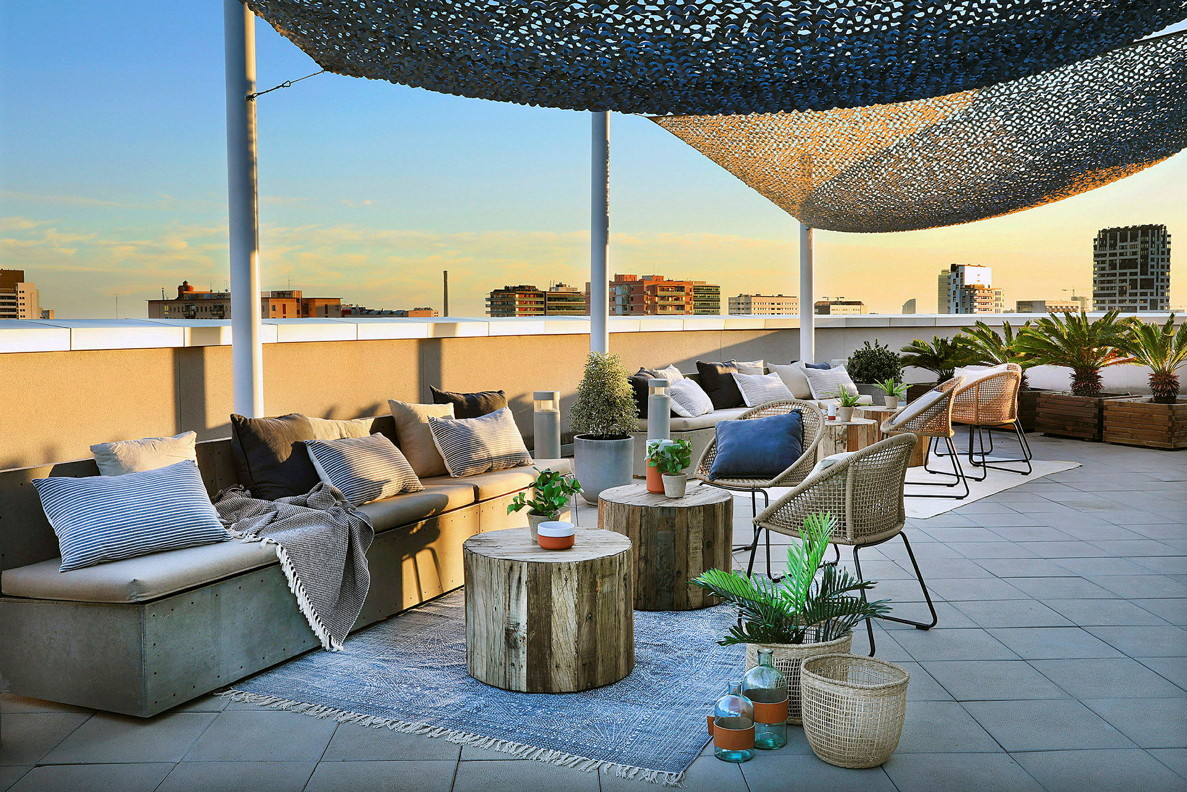 En takterrass med sittmöbler, bord och korgar dekorerade med växter och kuddar är avbildad. (AI-genererad text)