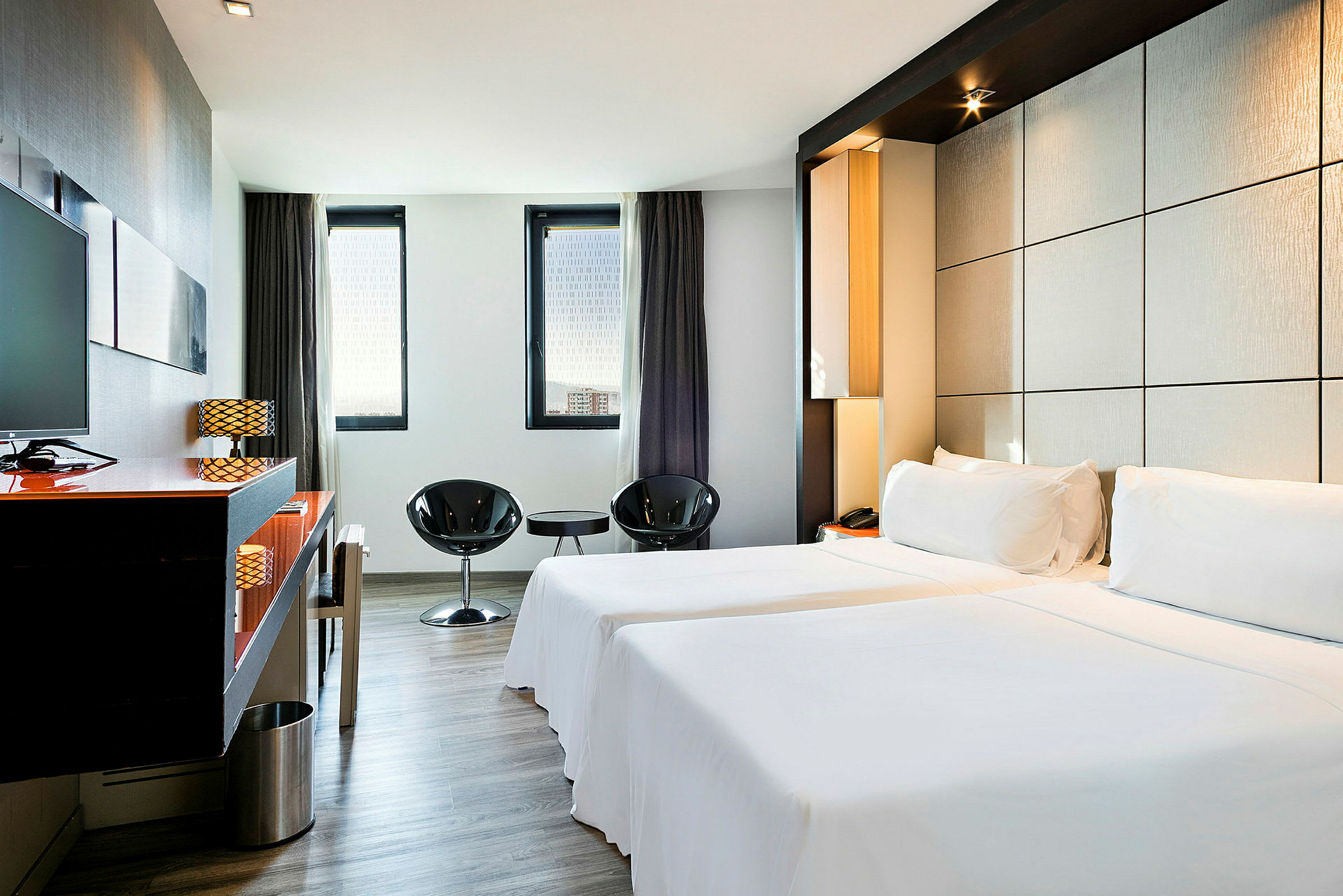 Ett elegant hotellrum med två enkelsängar, minimalistisk inredning och stora fönster som släpper in naturligt ljus. (AI-genererad text)