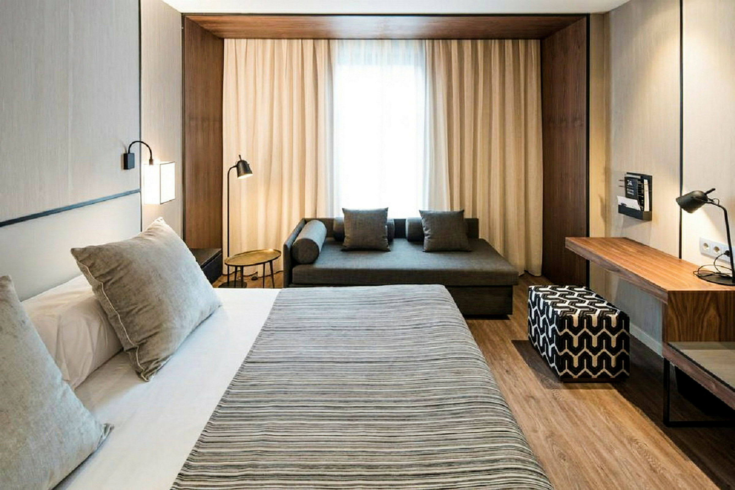 Ett modernt hotellrum med en stor säng, soffa och skrivbord. (AI-genererad text)
