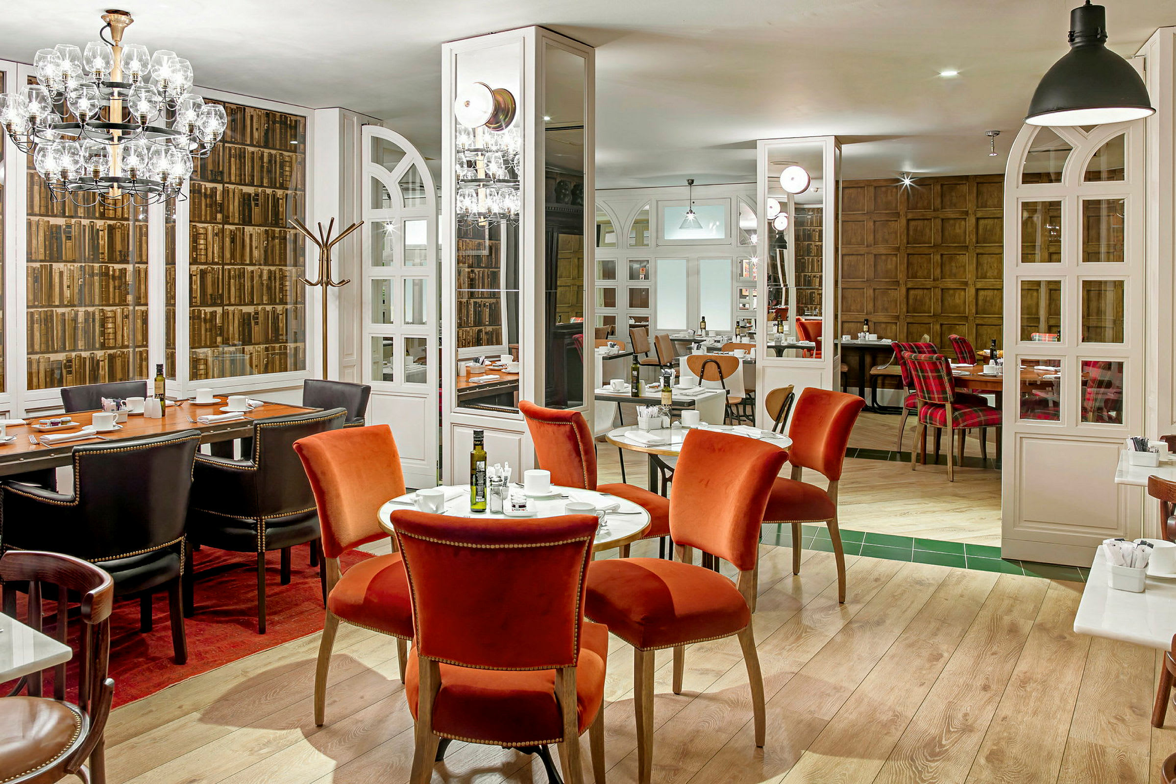 Ett interiör av en restaurang med bord och olika stolar i en elegant miljö. (AI-genererad text)
