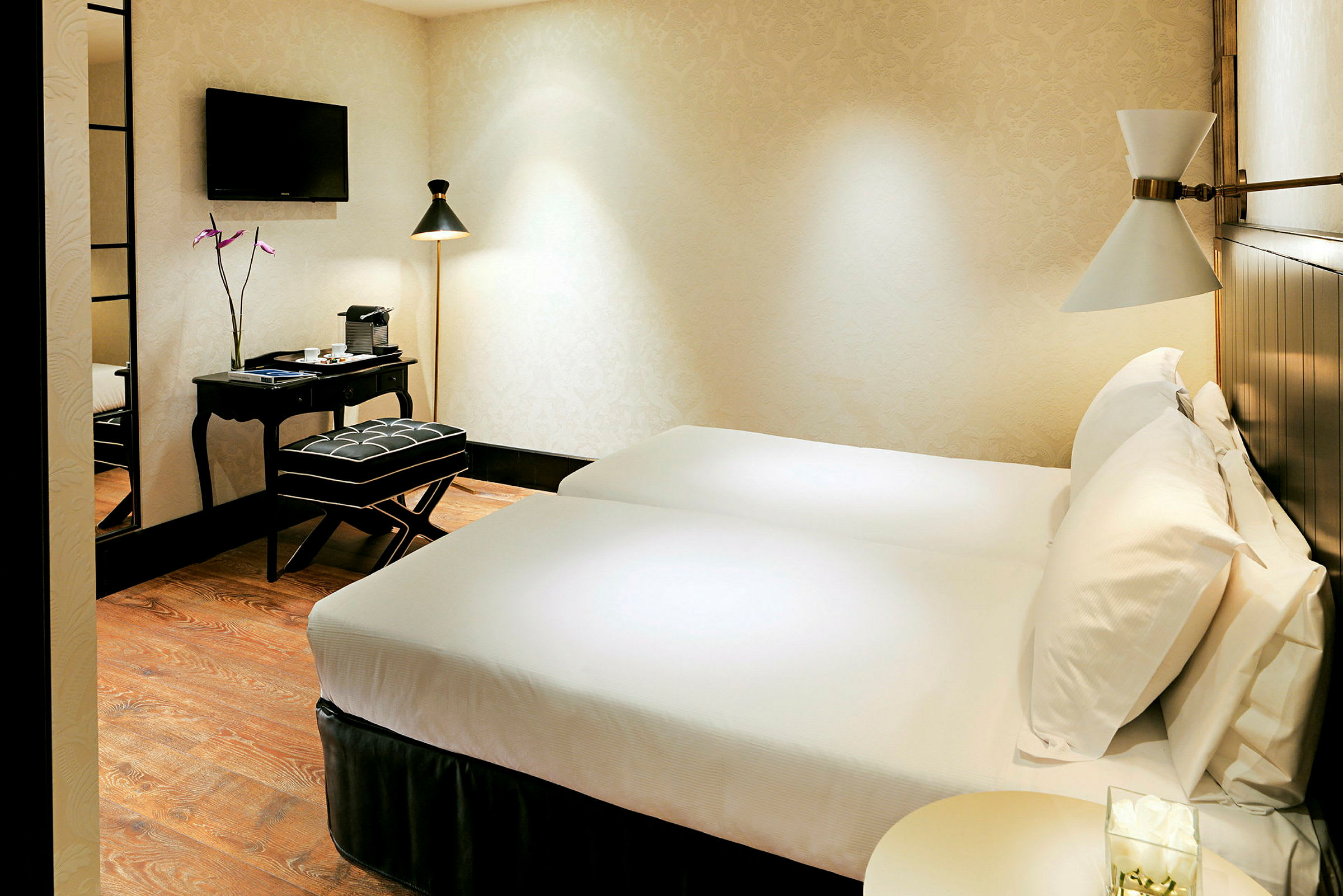 Ett hotellrum med två enkelsängar, ett skrivbord med en stol och en väggmonterad TV. (AI-genererad text)