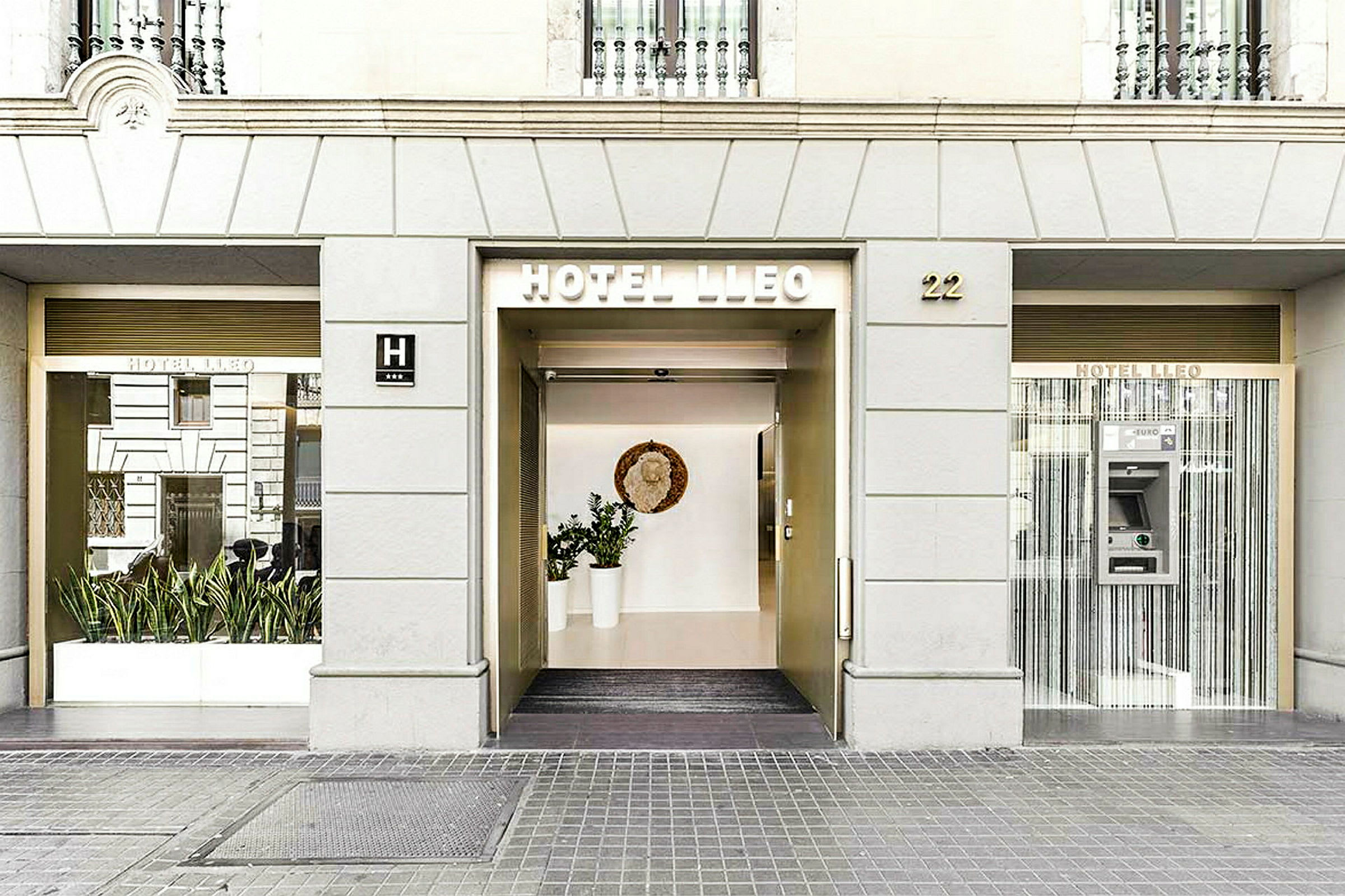 Bild av Hotel Lleos framdörr med stora glaspartier och en modern entré. (AI-genererad text)