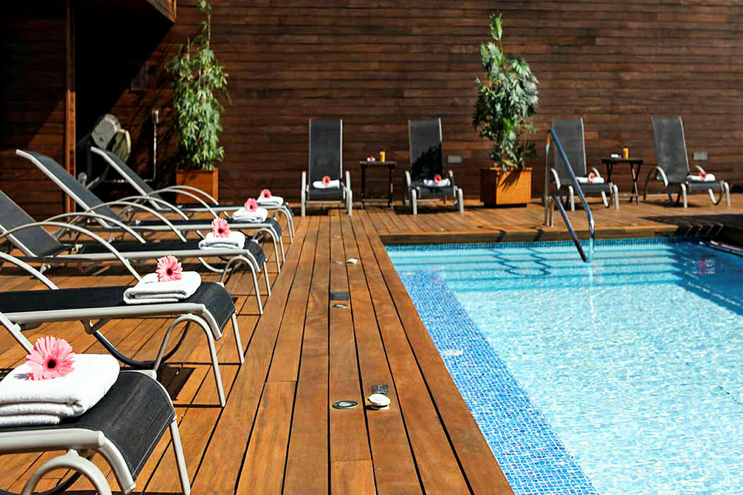 Solstolar med handdukar och blommor vid en pool med trädäck. (AI-genererad text)