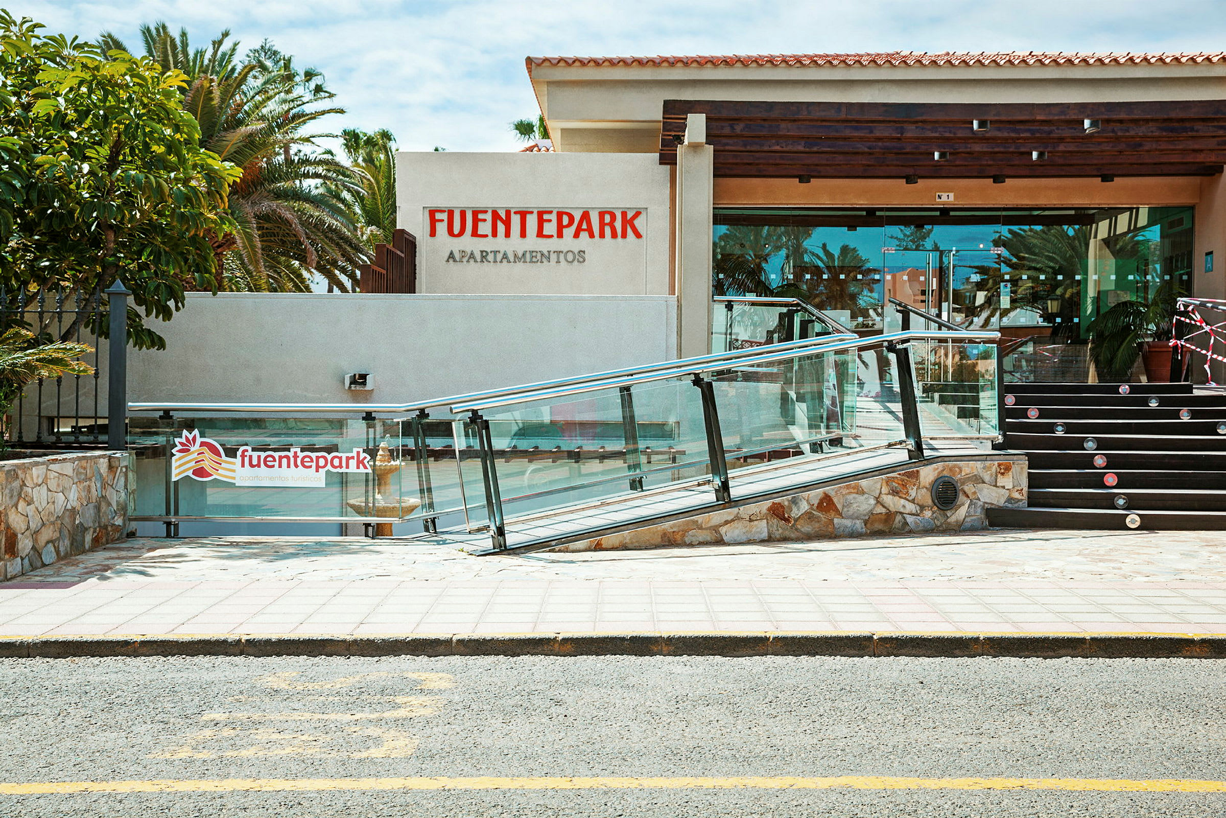 Entrén till Fuentepark Lägenheter med en ramp och trappa. (AI-genererad text)