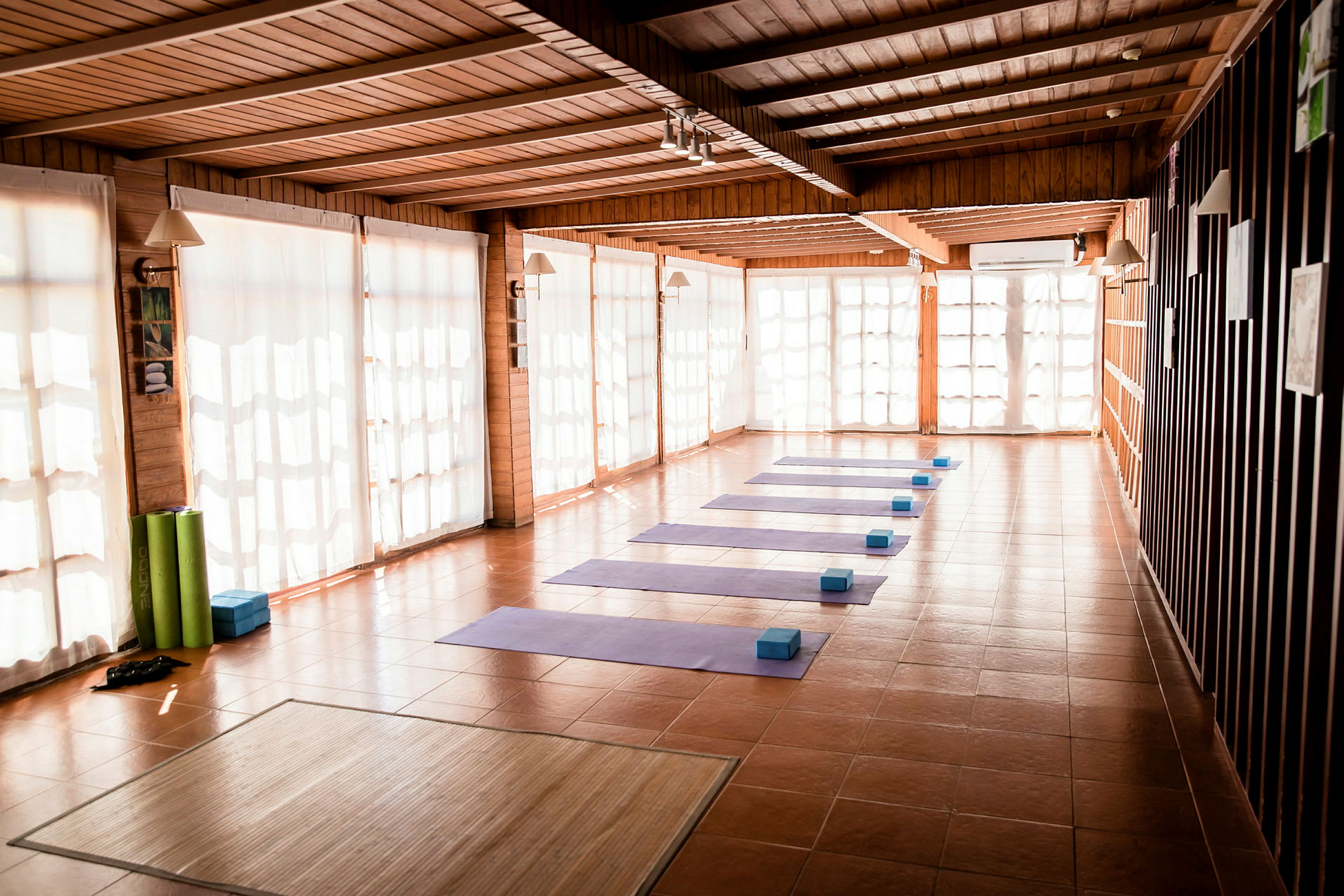 Ett solbelyst rum med yogamattor och block arrangerade på golvet. (AI-genererad text)