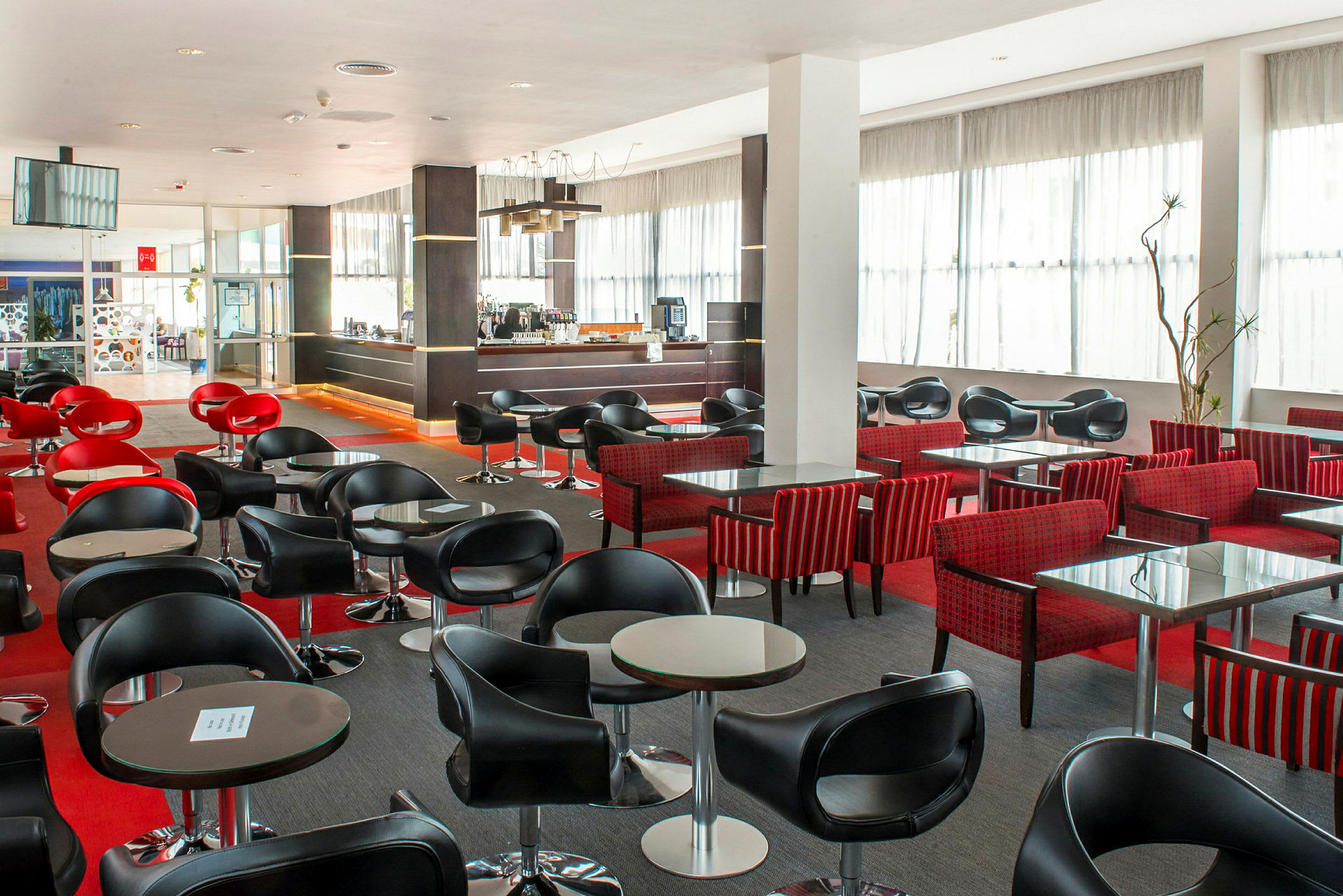 En modern kafé- eller barhörna med svarta och röda stolar och små bord. (AI-genererad text)