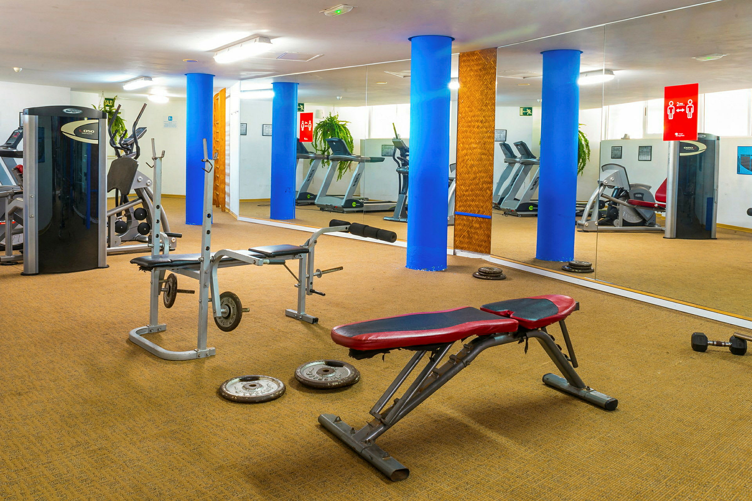 Ett gym med träningsredskap, bänkar och speglar. (AI-genererad text)