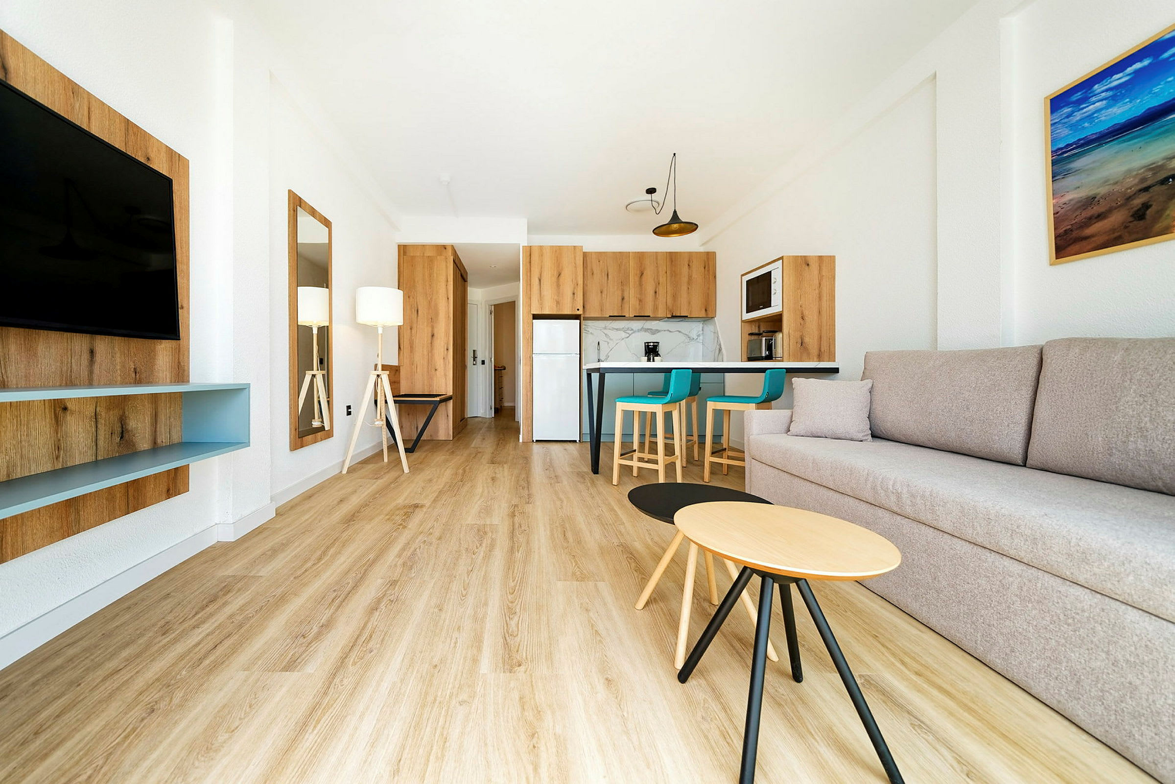 Modernt inrett vardagsrum med soffa, TV, köksdel och matplats. (AI-genererad text)