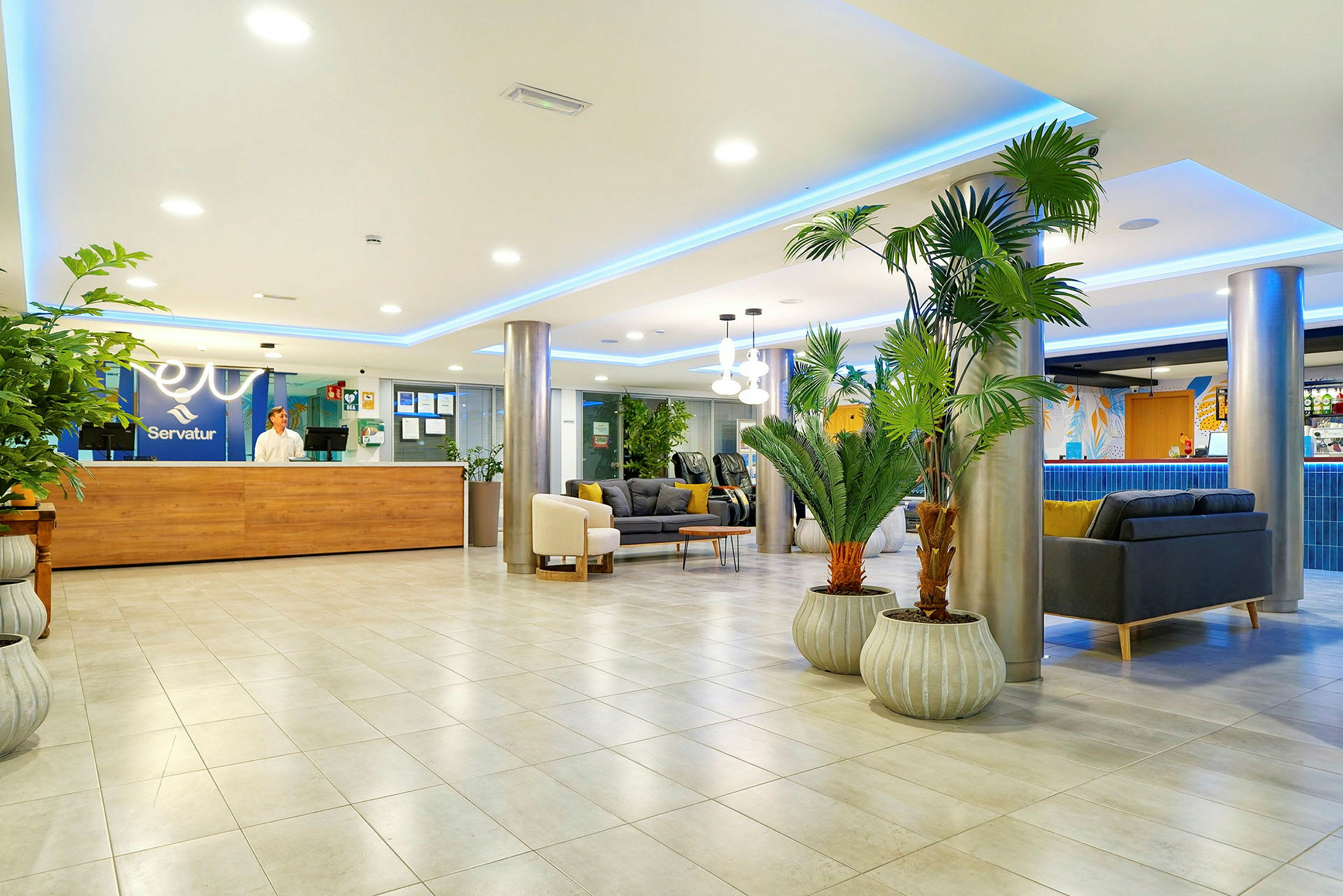 Ett modernt hotellobbyområde med sittgrupper, växter och en receptionsdisk. (AI-genererad text)