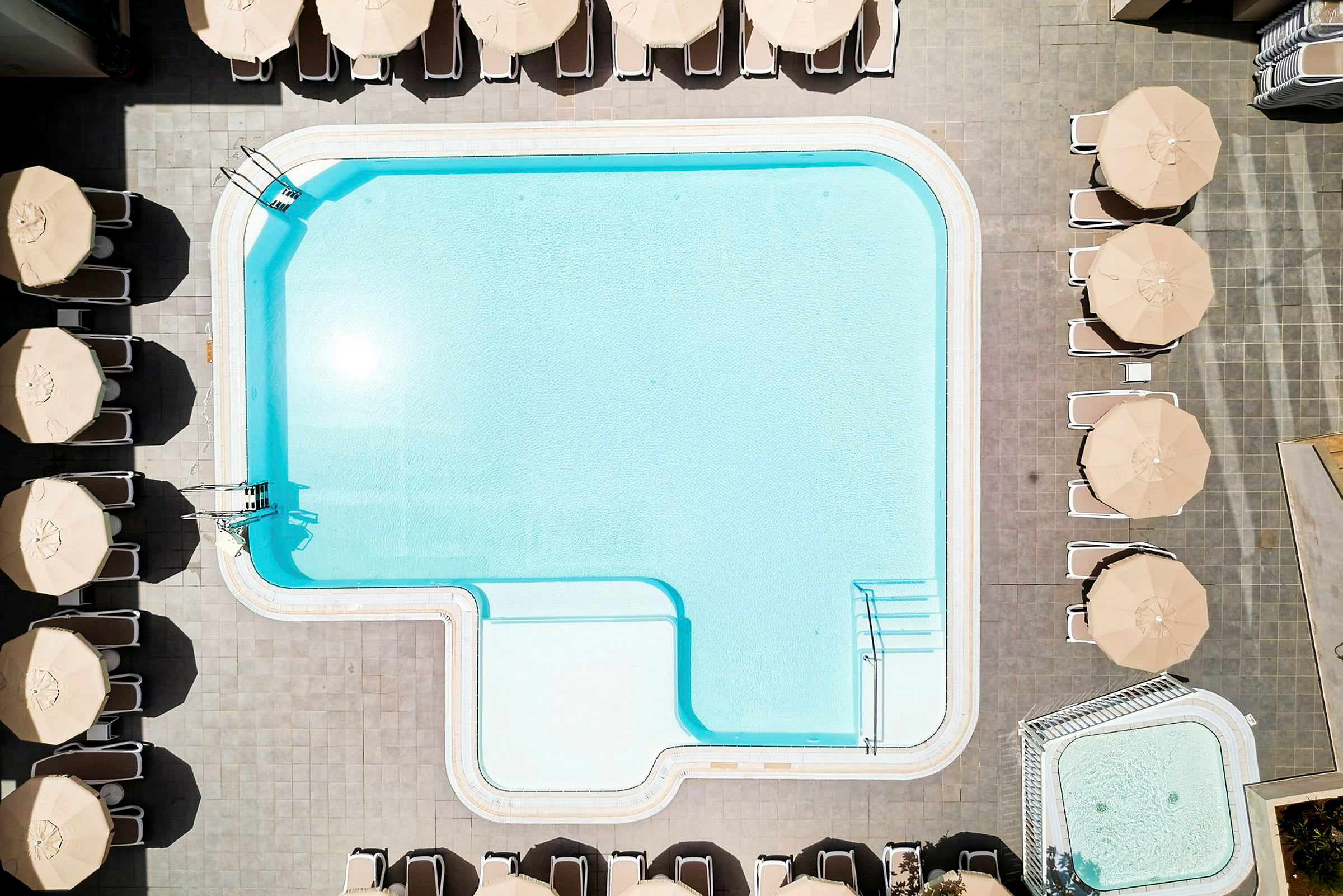 En utomhuspool med omgivande parasoller och solstolar. (AI-genererad text)