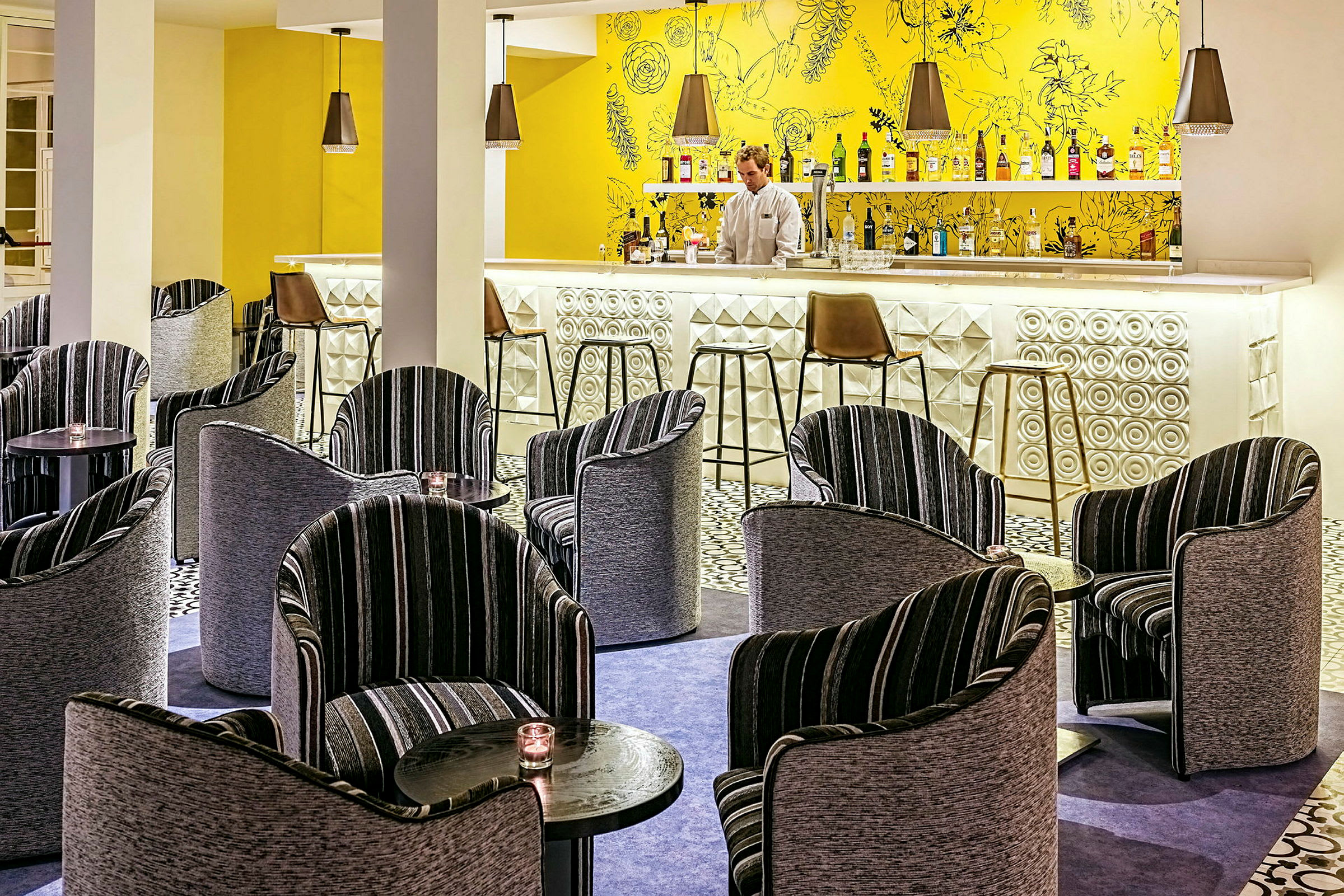 En hotellbar med färgglad inredning, inklusive moderna stolar och små bord. (AI-genererad text)