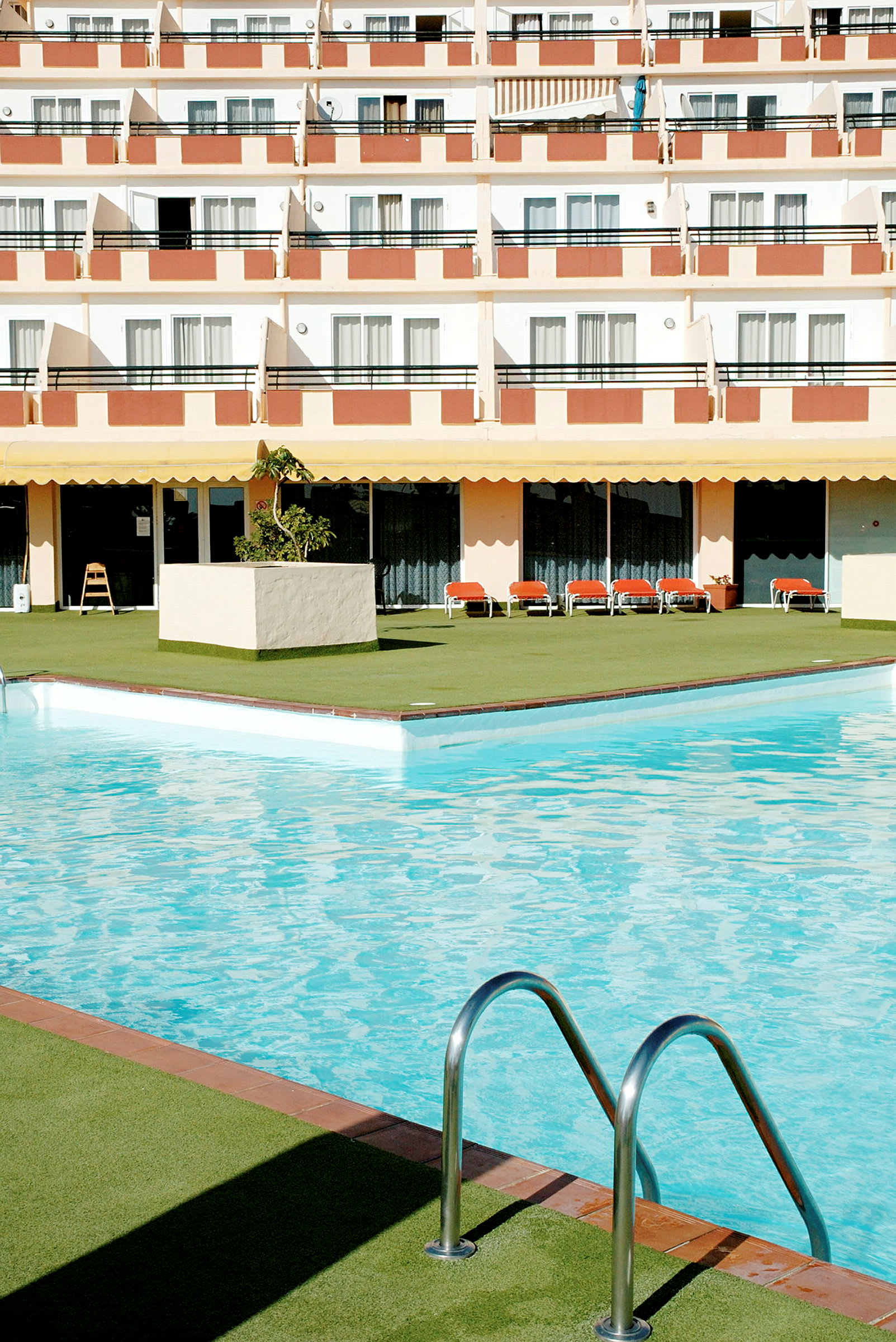Bild av en hotellpool med solstolar och balkonger i bakgrunden. (AI-genererad text)