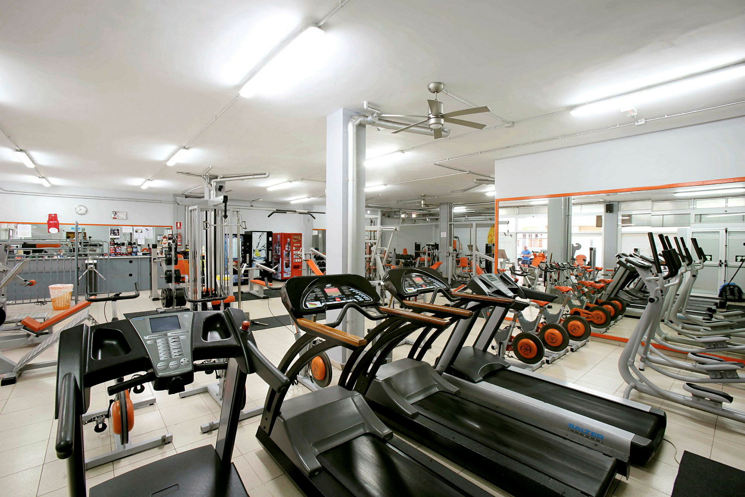 Ett gym med olika träningsmaskiner och utrustning som löpband och cyklar. (AI-genererad text)
