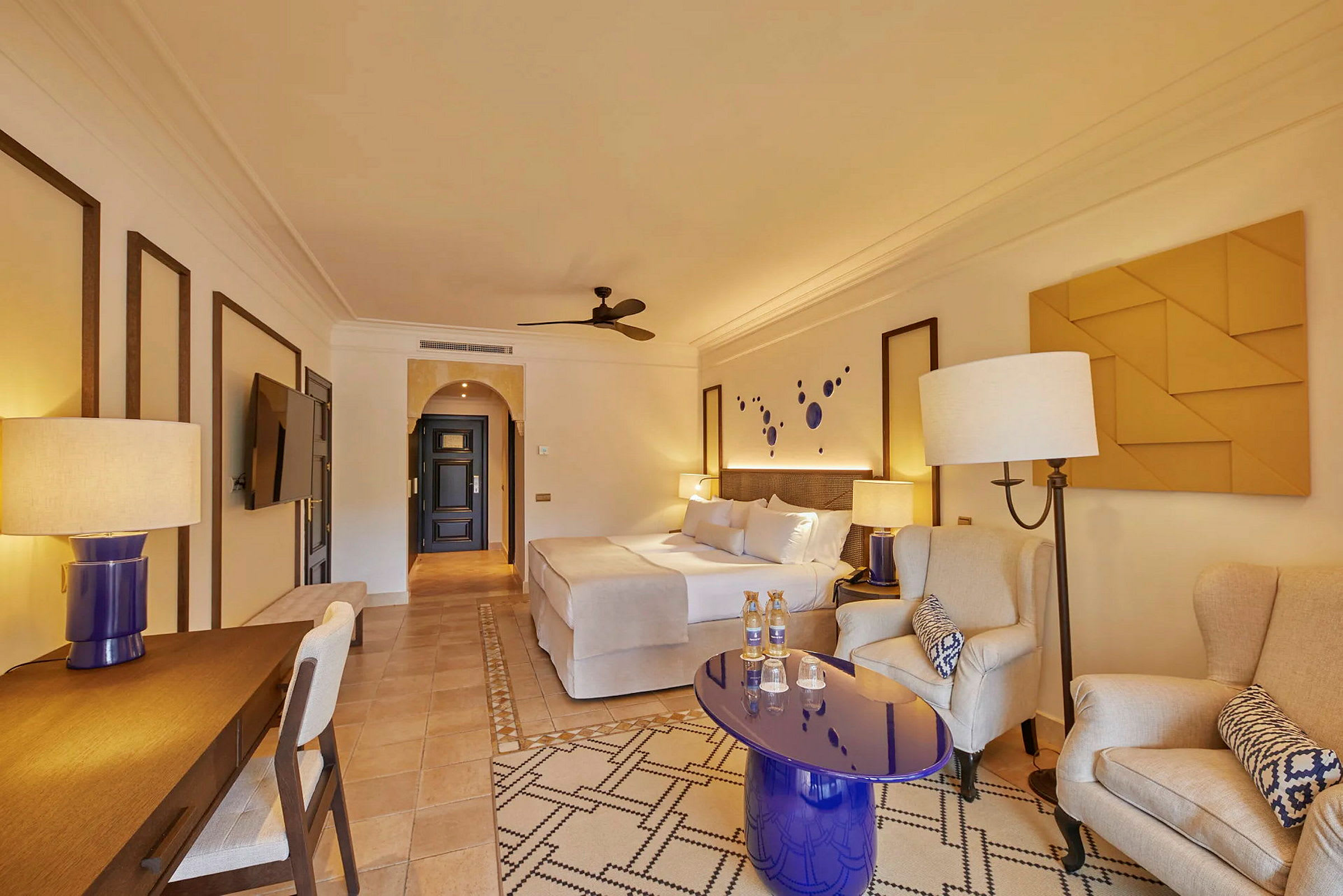 Ett elegant inrett hotellrum med en stor säng, sittgrupp och skrivbord. (AI-genererad text)
