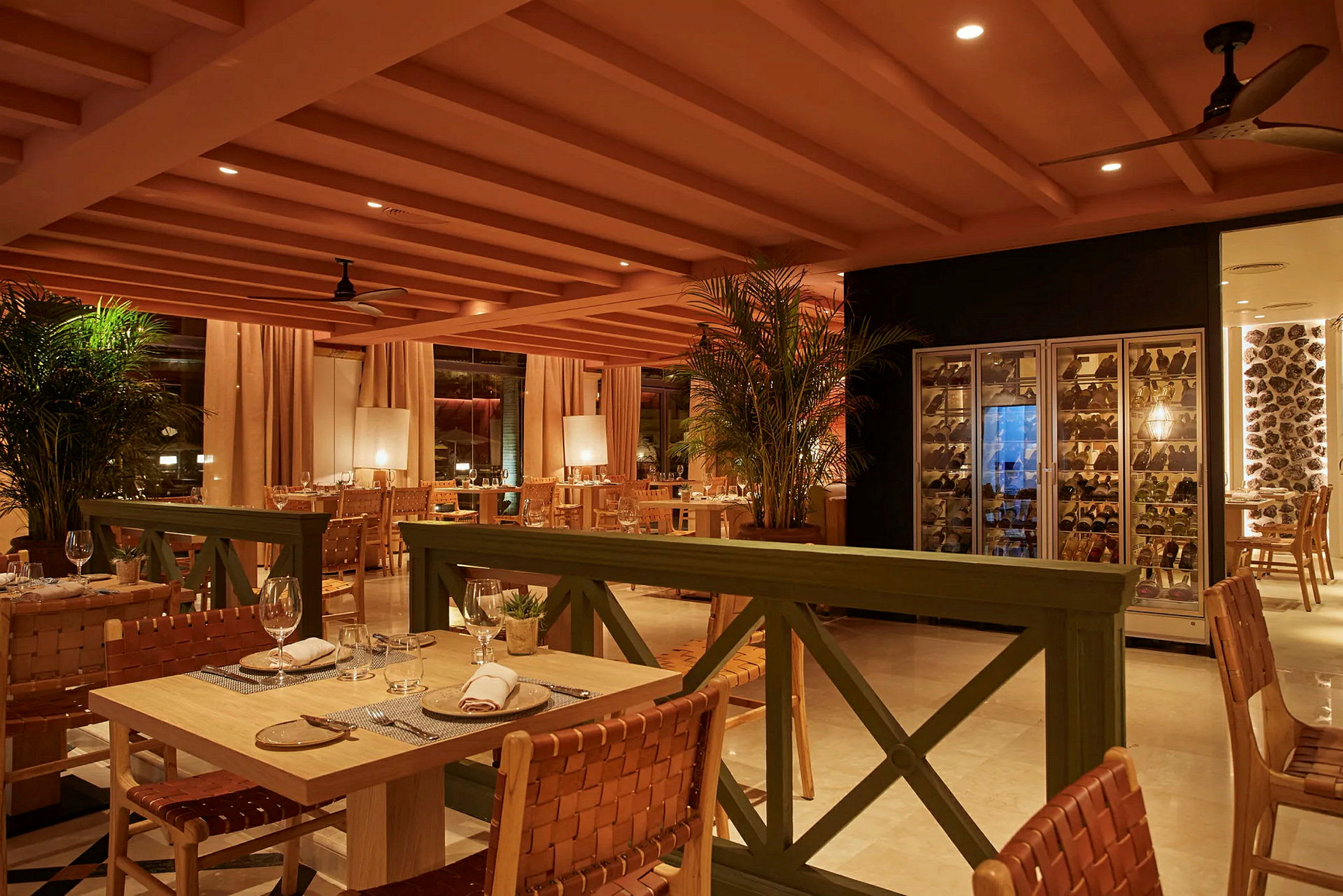 Bild av en elegant restaurang med bord och stolar, vinförvaringsskåp till höger och varm belysning. (AI-genererad text)