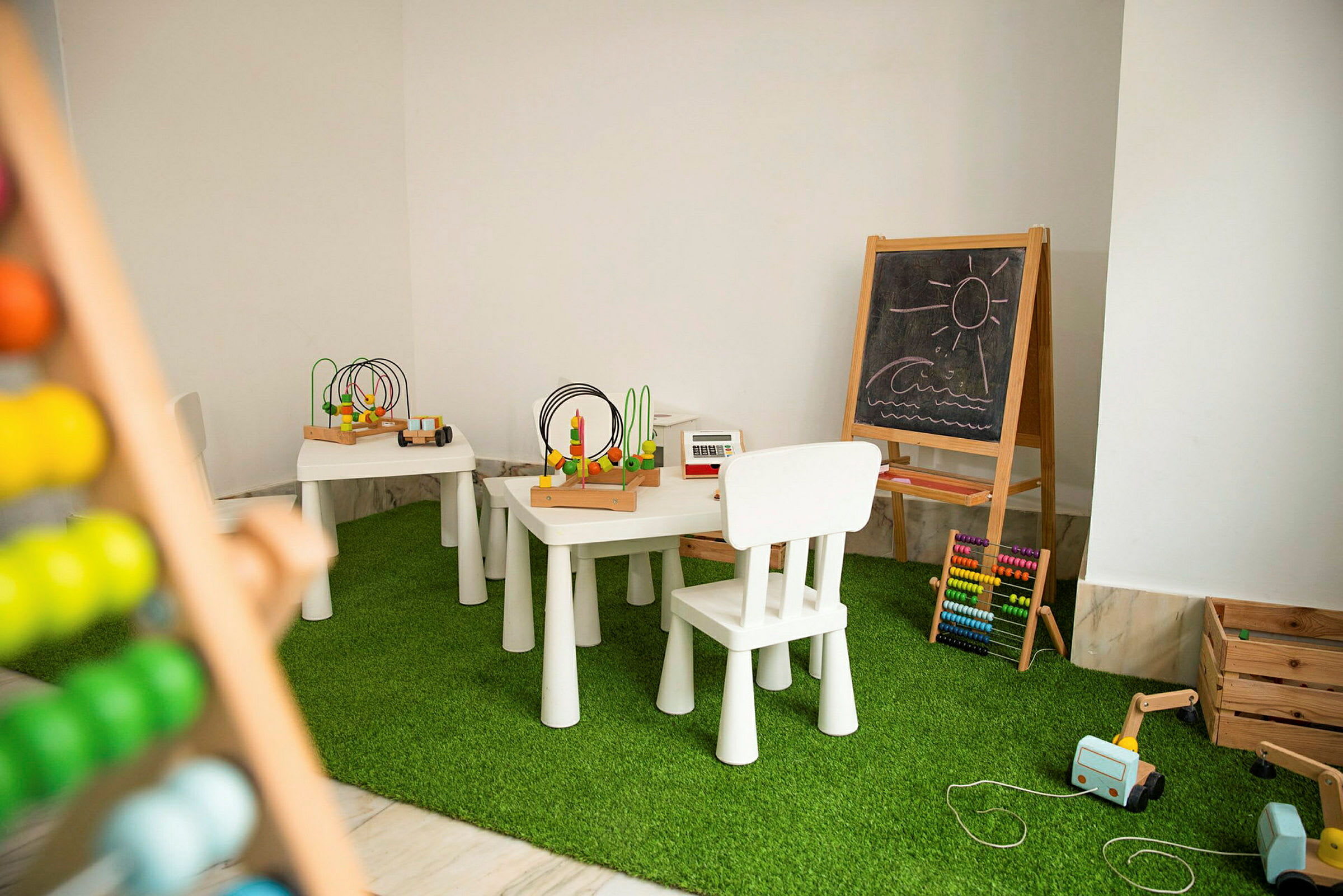 Ett lekrum med små bord och stolar, pedagogiska leksaker och en griffeltavla. (AI-genererad text)