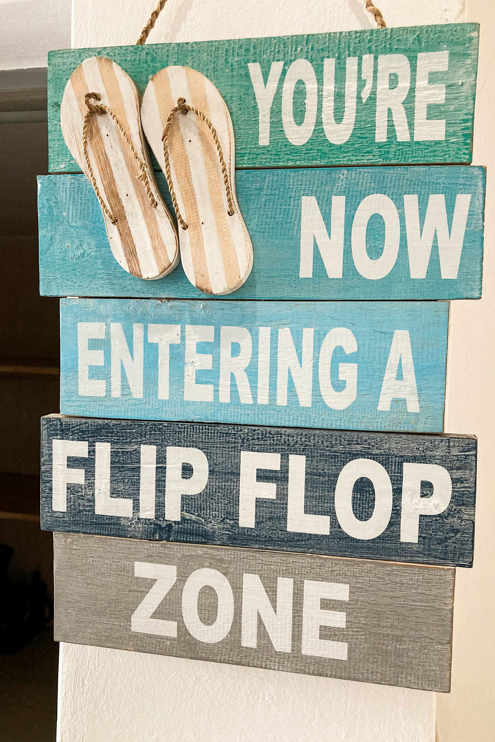 En skylt med texten 'You're now entering a flip flop zone' och två hängande sandaler upptill. (AI-genererad text)