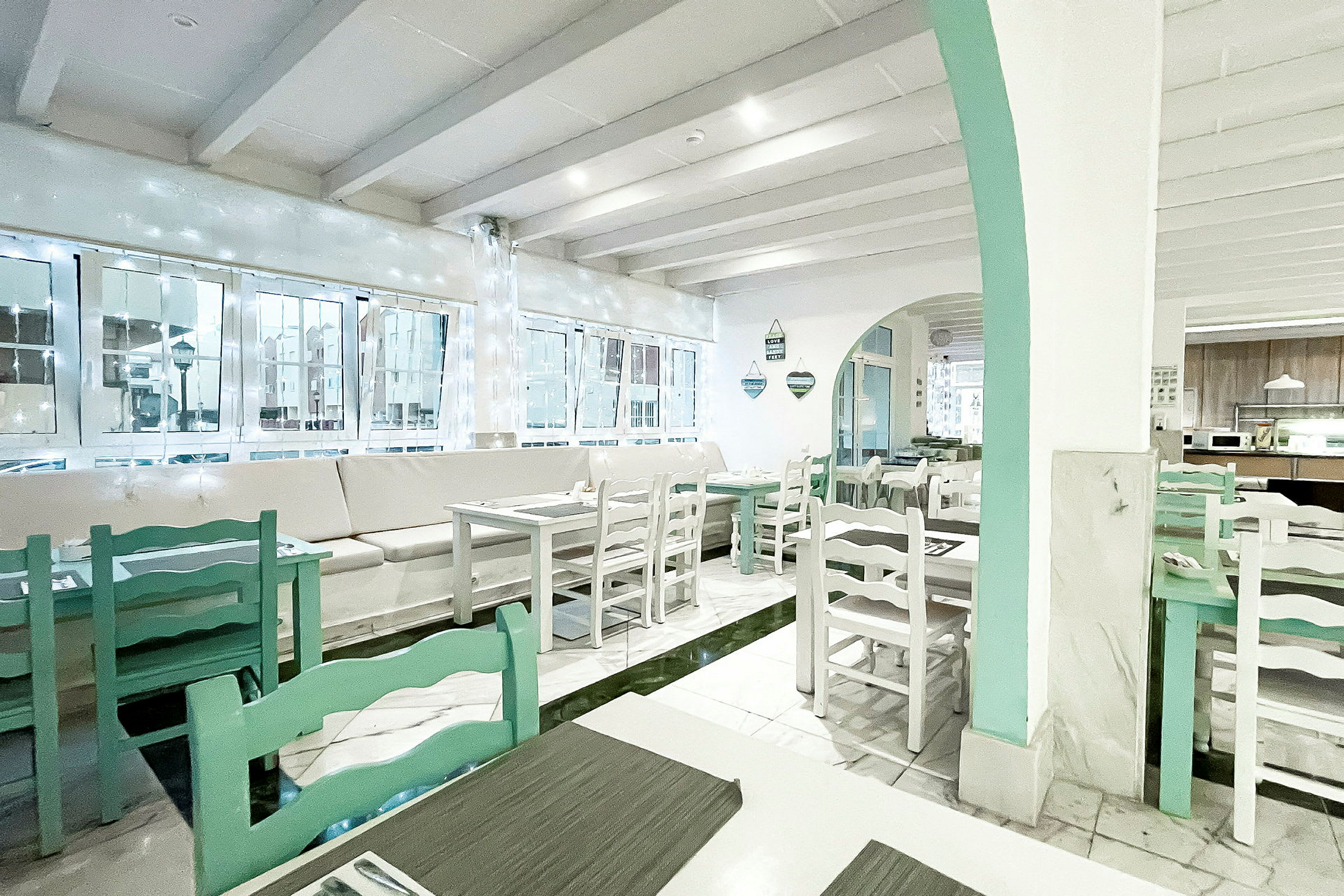 Ett ljust och luftigt kafé eller restaurang med vita väggar och ljusgröna möbler. (AI-genererad text)