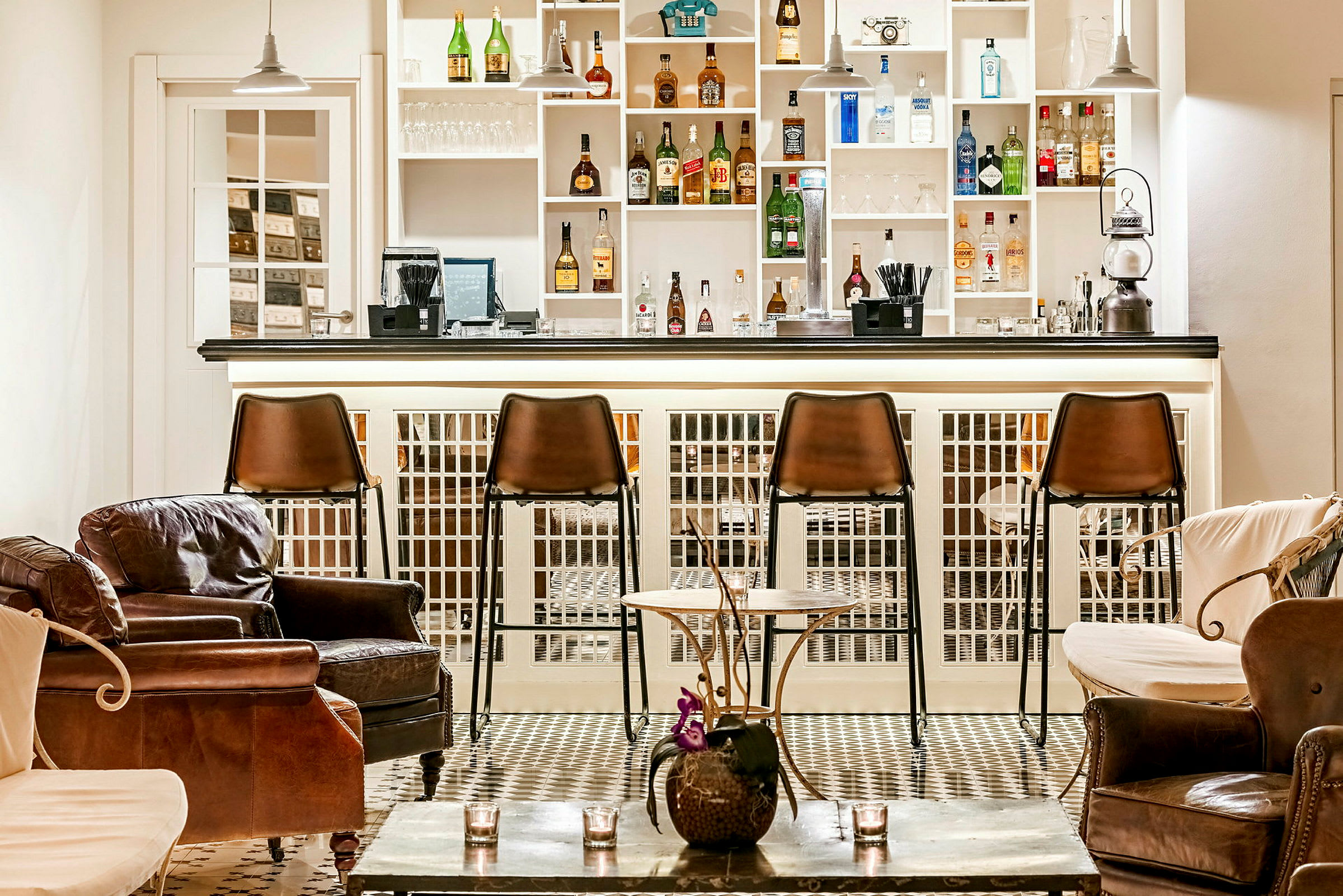Bild av en elegant bar med bruna barstolar och bekväma läderfåtöljer. Hyllorna bakom disken är fyllda med flaskor och glas. (AI-genererad text)