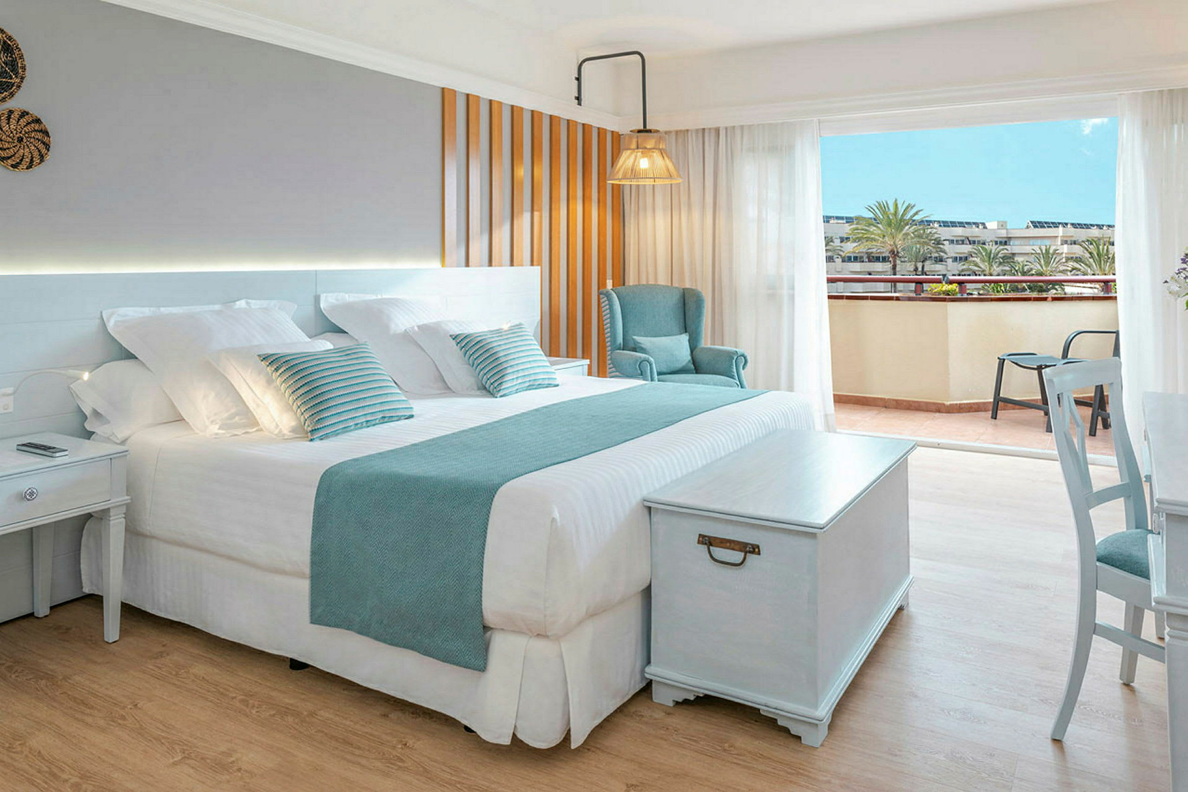 Ett ljust och elegant hotellrum med en stor säng, sittplats och tillgång till en balkong. (AI-genererad text)