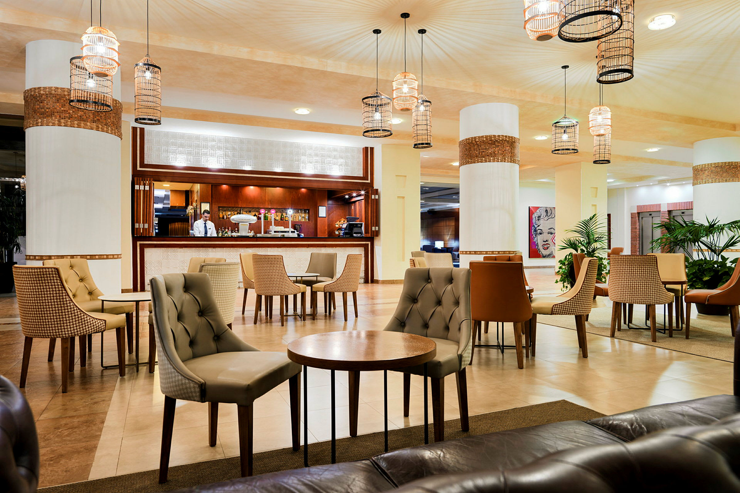 Elegant hotellobby med möblerade sittgrupper och en bemannad receptionsdisk. (AI-genererad text)