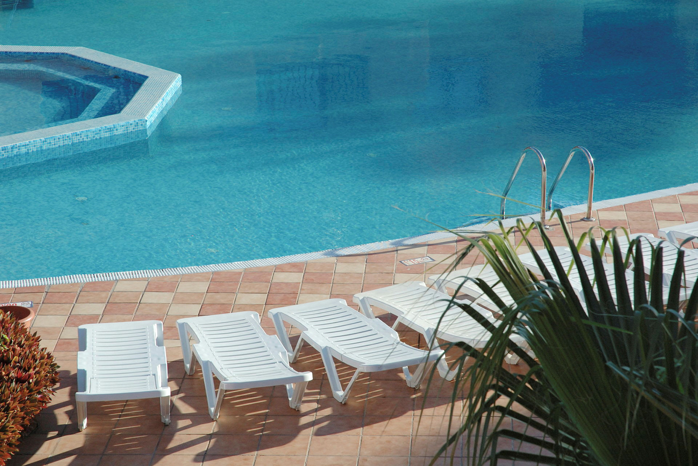 Solstolar vid en pool. (AI-genererad text)